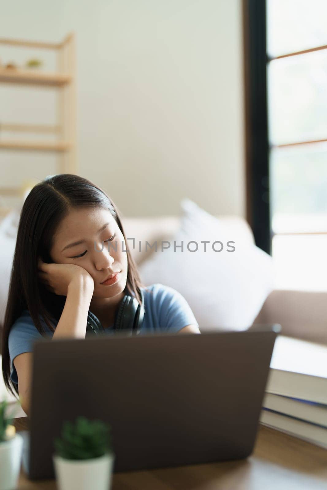 Studying online, beautiful Asian female student show symptoms burnout syndrome student studying online at home by Manastrong