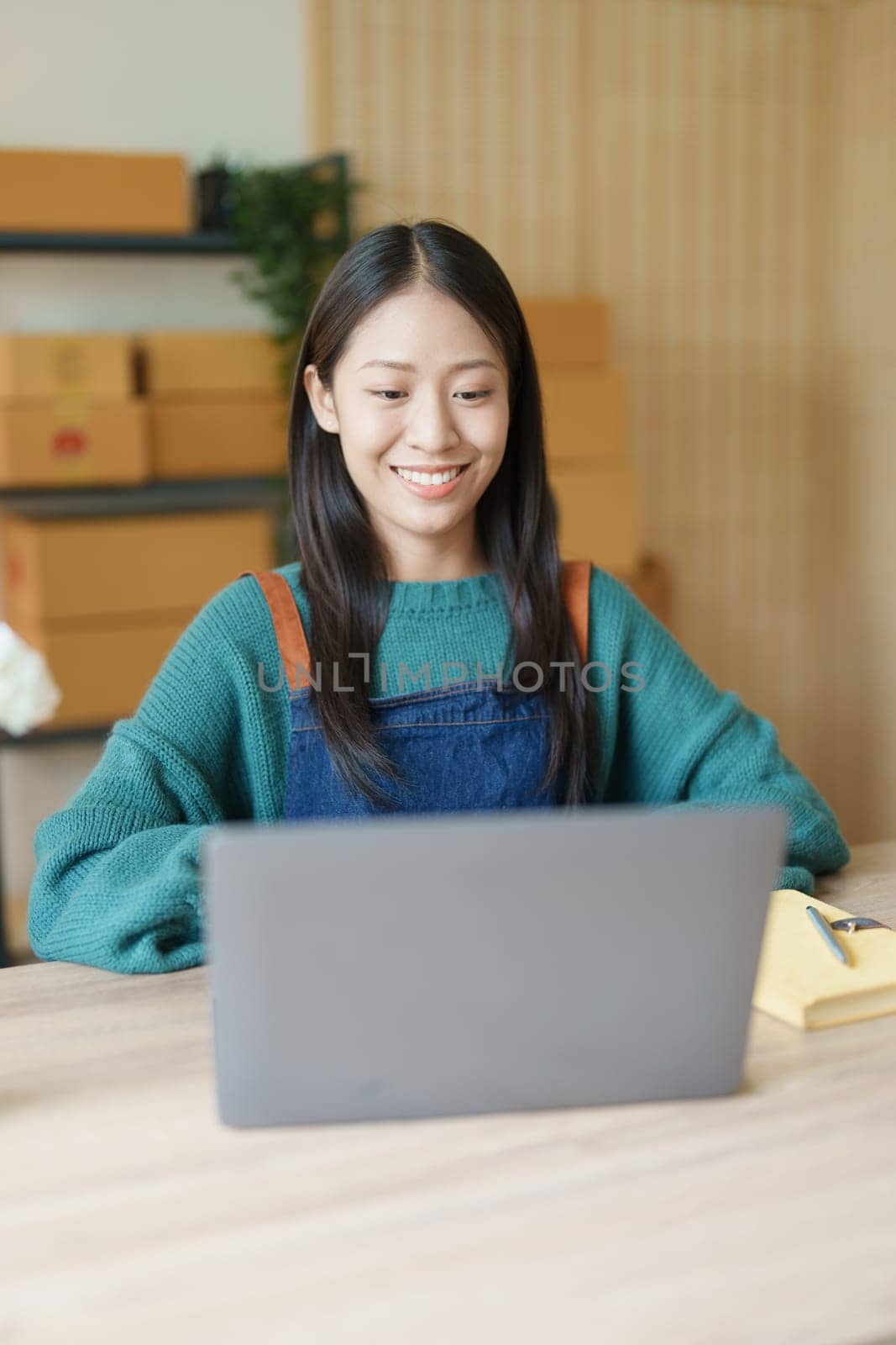 Starting small business entrepreneur of independent young Asian woman online seller is using computer and taking orders to pack products for delivery to customers. SME delivery concept by Manastrong