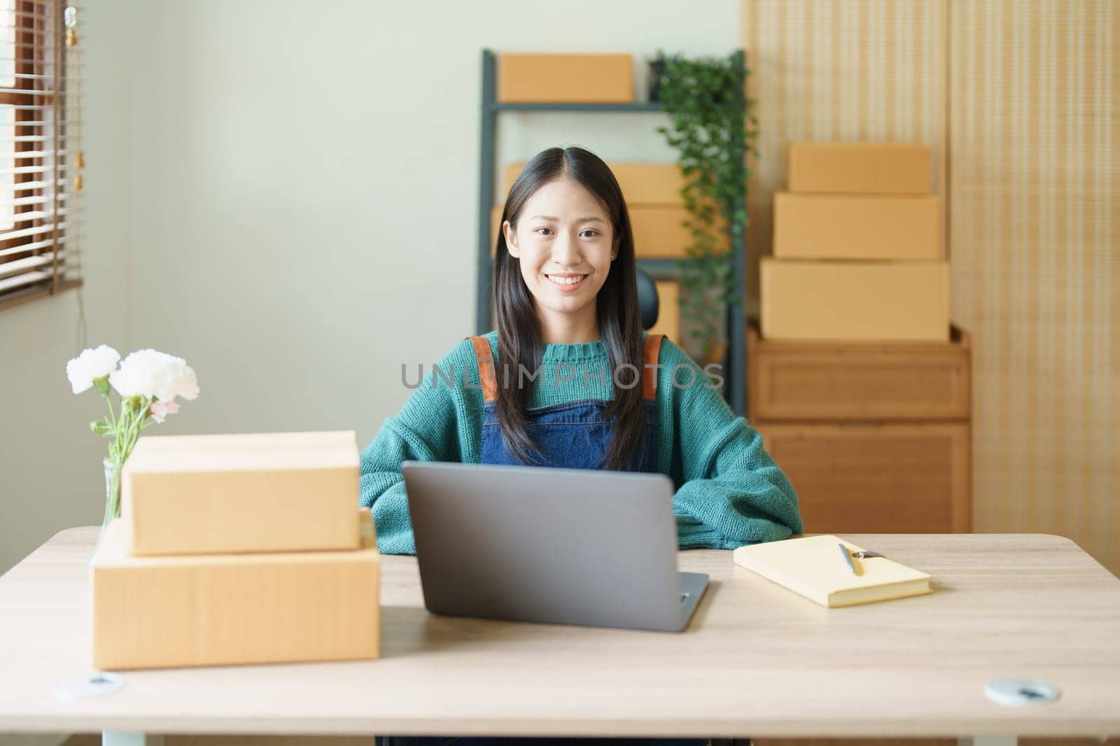 Starting small business entrepreneur of independent young Asian woman online seller is using computer and taking orders to pack products for delivery to customers. SME delivery concept by Manastrong