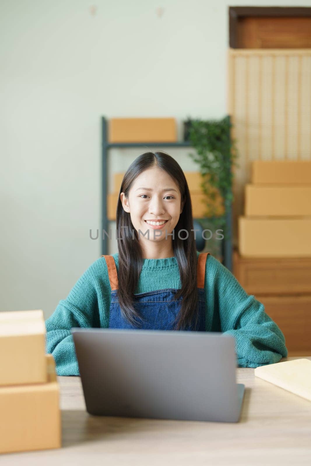 Starting small business entrepreneur of independent young Asian woman online seller is using computer and taking orders to pack products for delivery to customers. SME delivery concept by Manastrong