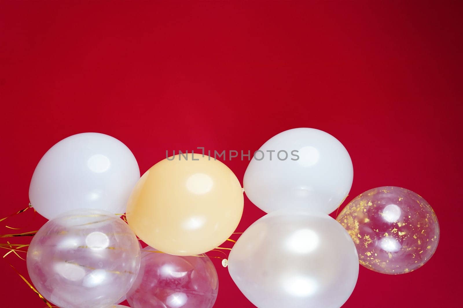 Vertical photo of white and transparent balloons on red burgundy background. Space for text. High quality photo