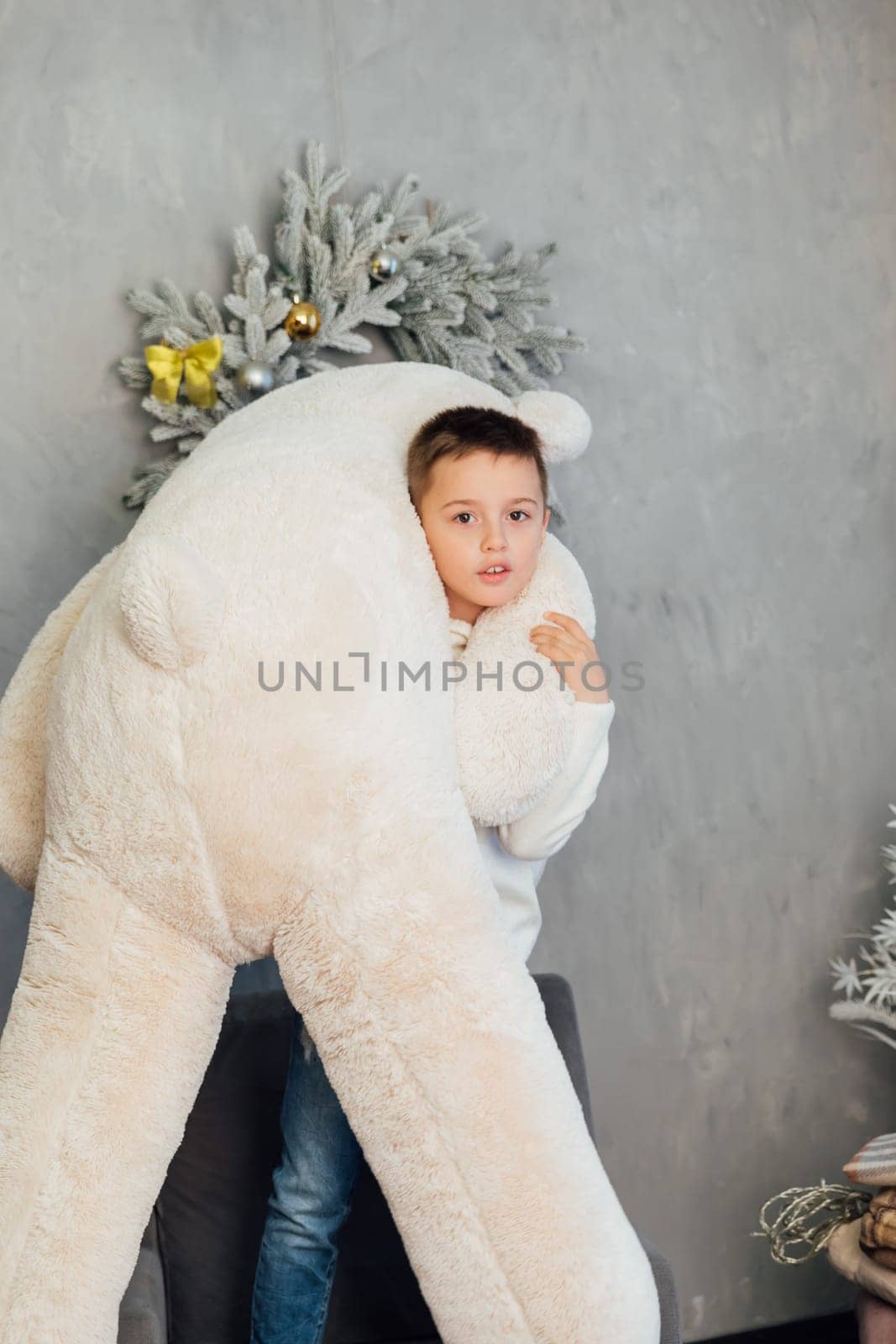 Boy holding a big teddy bear at the Christmas tree for the new year by Simakov