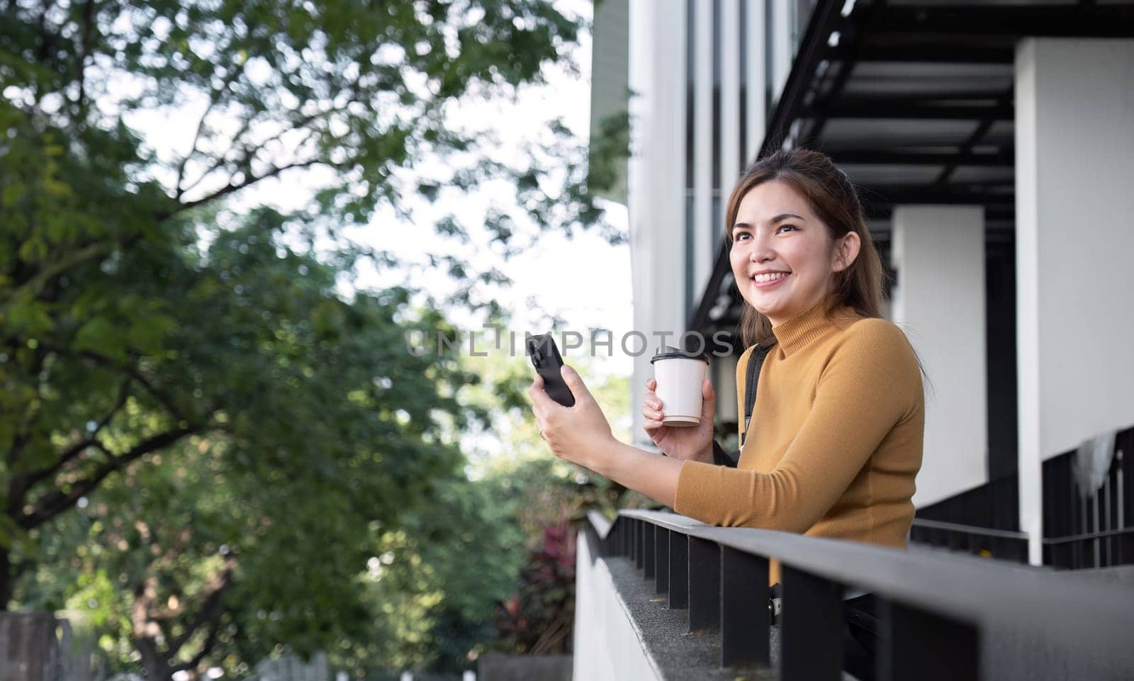 Successful Asian businesswoman standing and smiling Stay in the city using an application on your mobile phone. Read news on your smartphone fast connection Check out the outdoor mobile app by wichayada