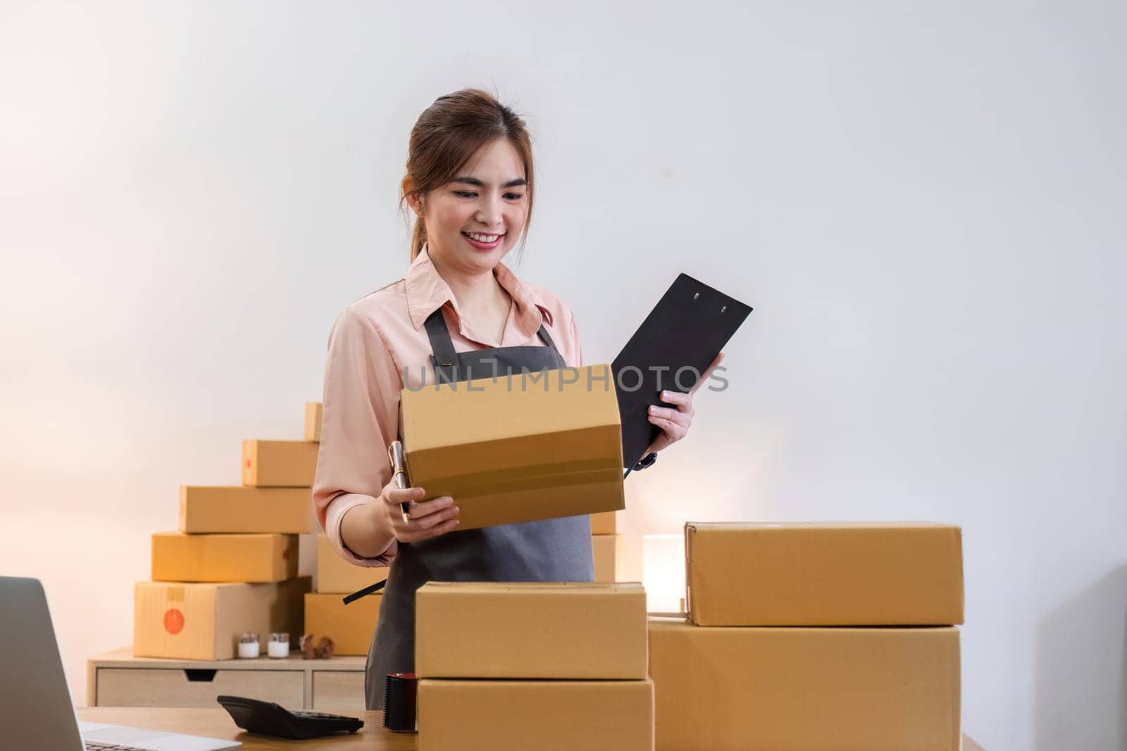 Portrait of starting a small business SME business owner Female entrepreneur working on merchandise boxes Receipts and checks online orders to prepare boxes for seller to customers. by wichayada
