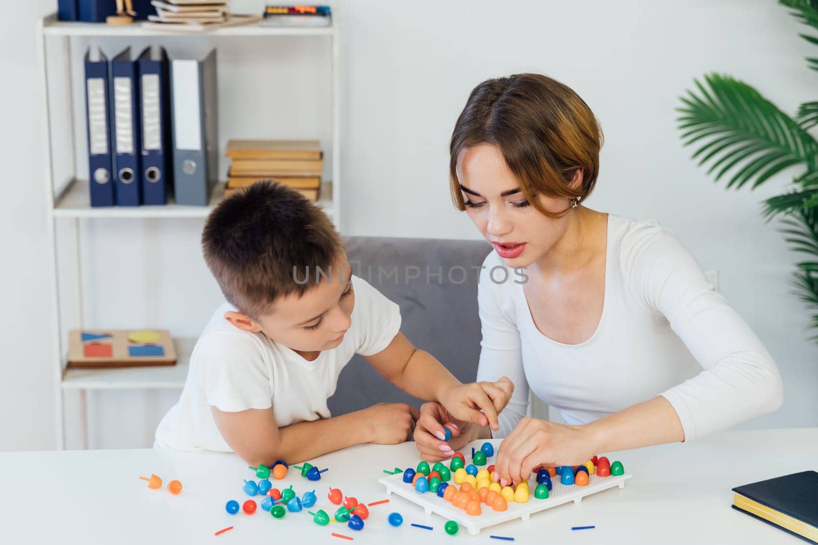 Teacher playing educational games with boy at school by Simakov