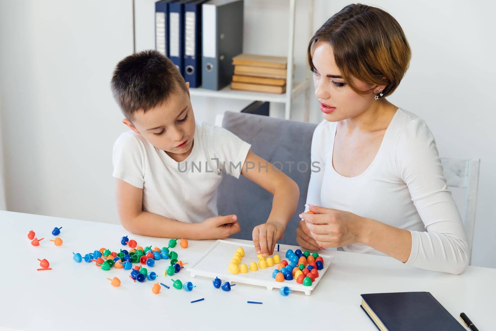 Teacher playing educational games with boy at school by Simakov