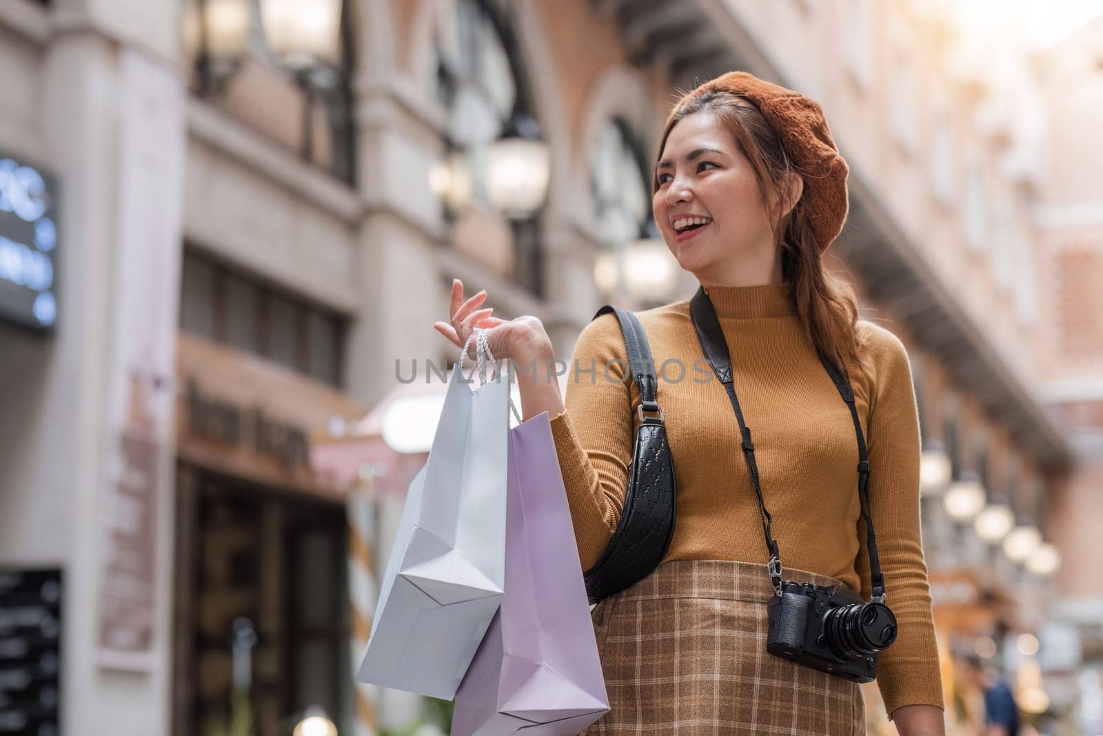 Beautiful Asian woman holding shopping bags and smiling while shopping on Black Friday outside the mall by wichayada