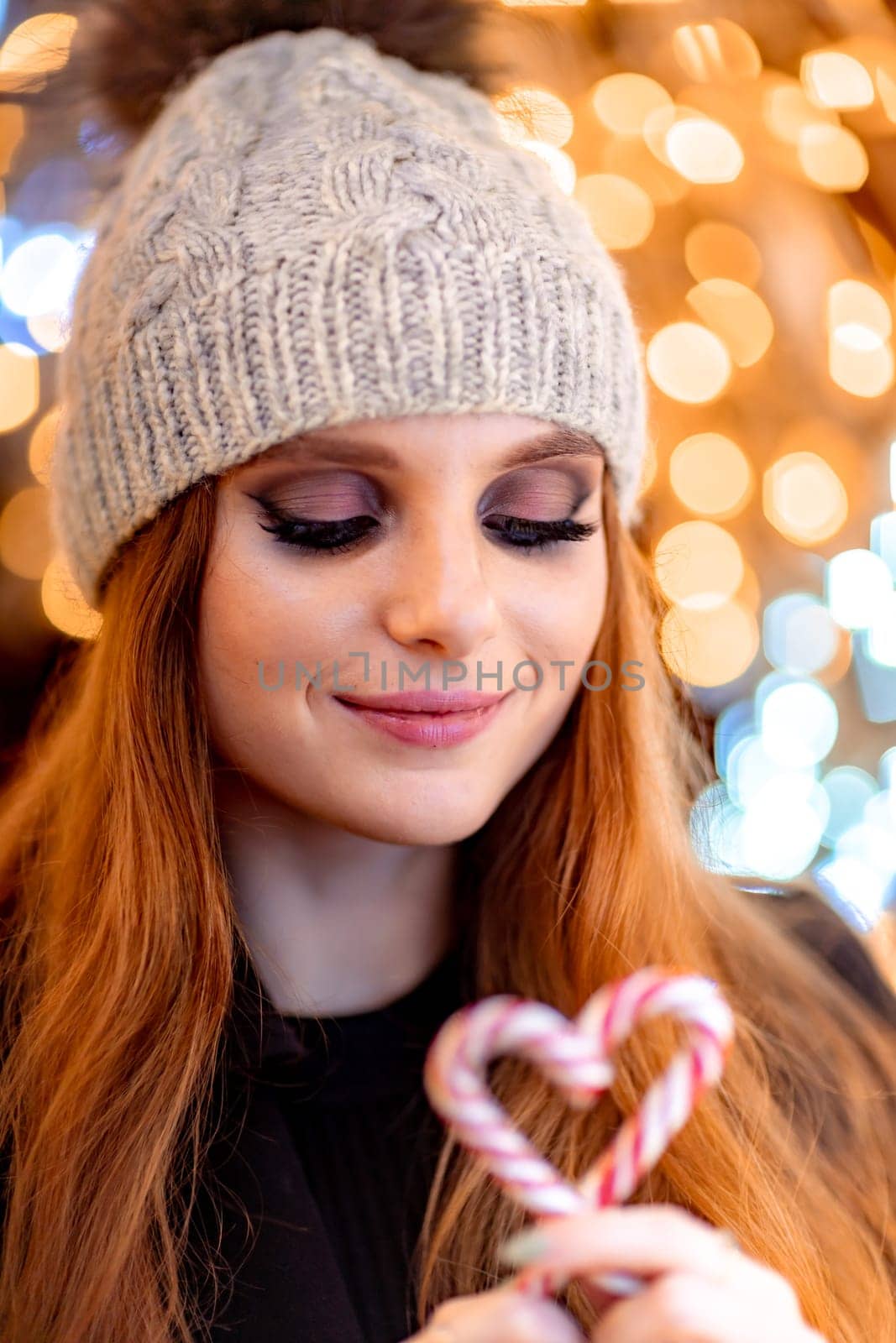 Christmas mood. Woman with long hair in sity decorated for Christmas. She is dressed in a black coat