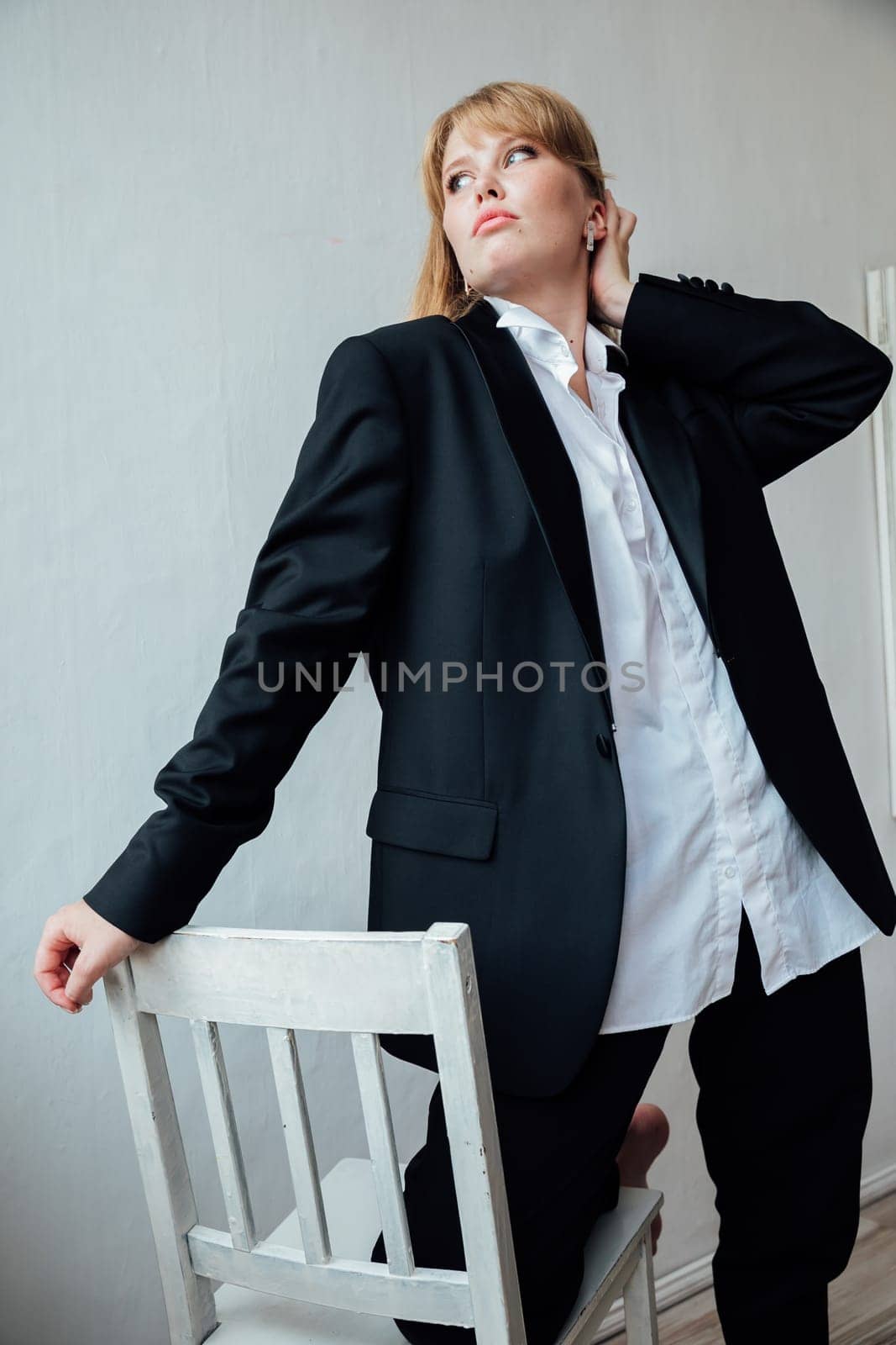 Beautiful fashionable woman in black business suit sitting on a chair