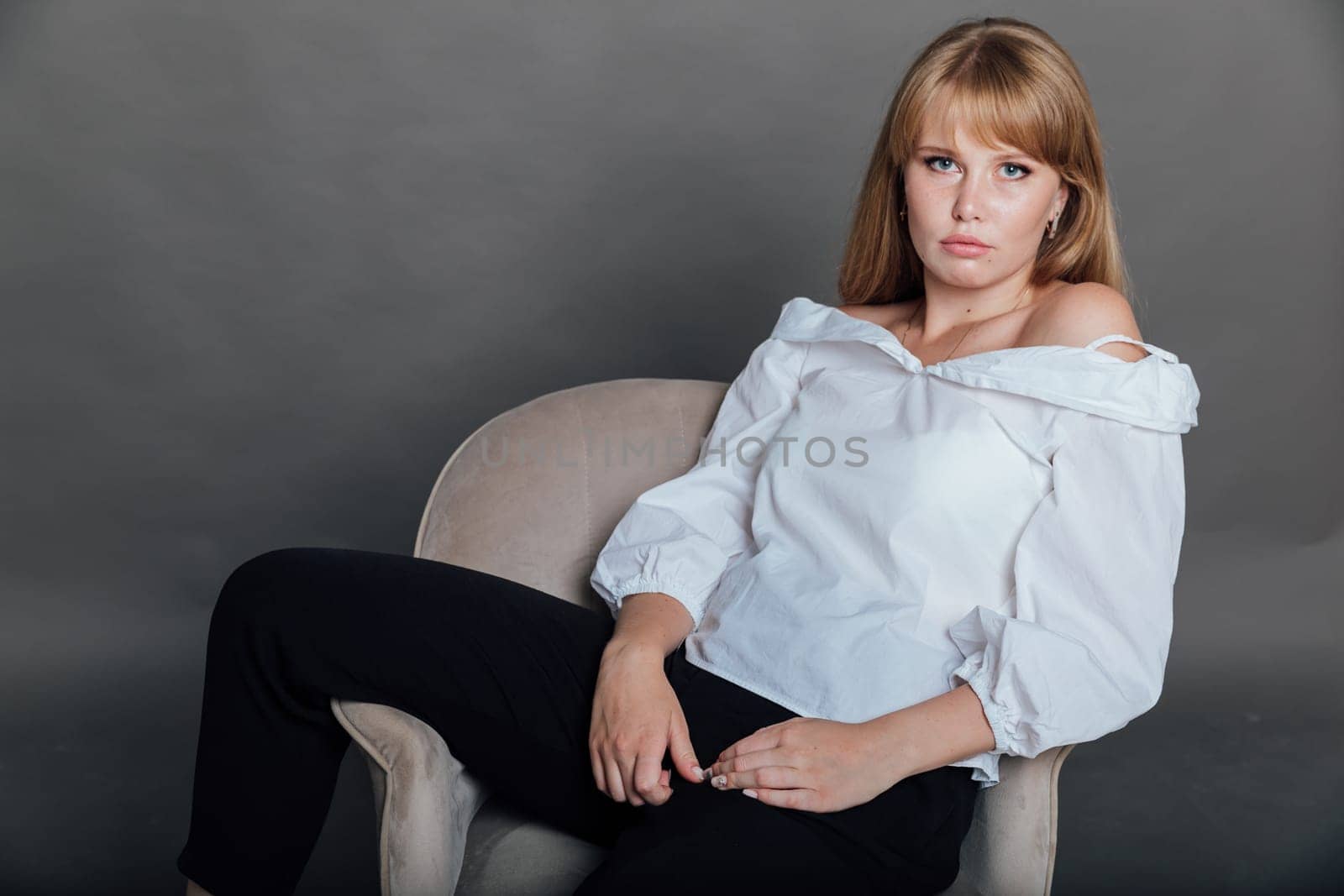 Beautiful young woman in white blouse and black pants sitting by Simakov