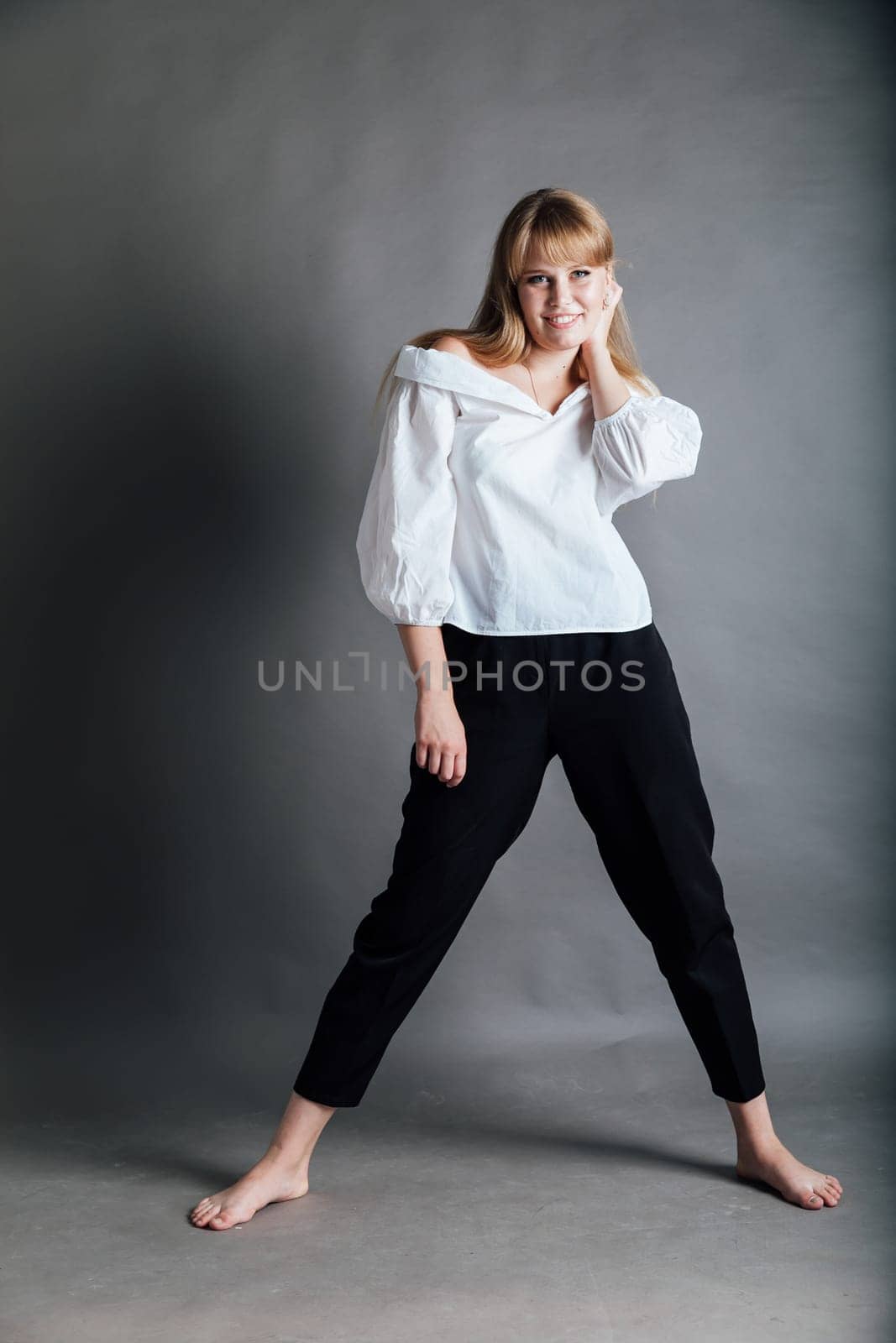 Beautiful young woman in white blouse and black pants by Simakov