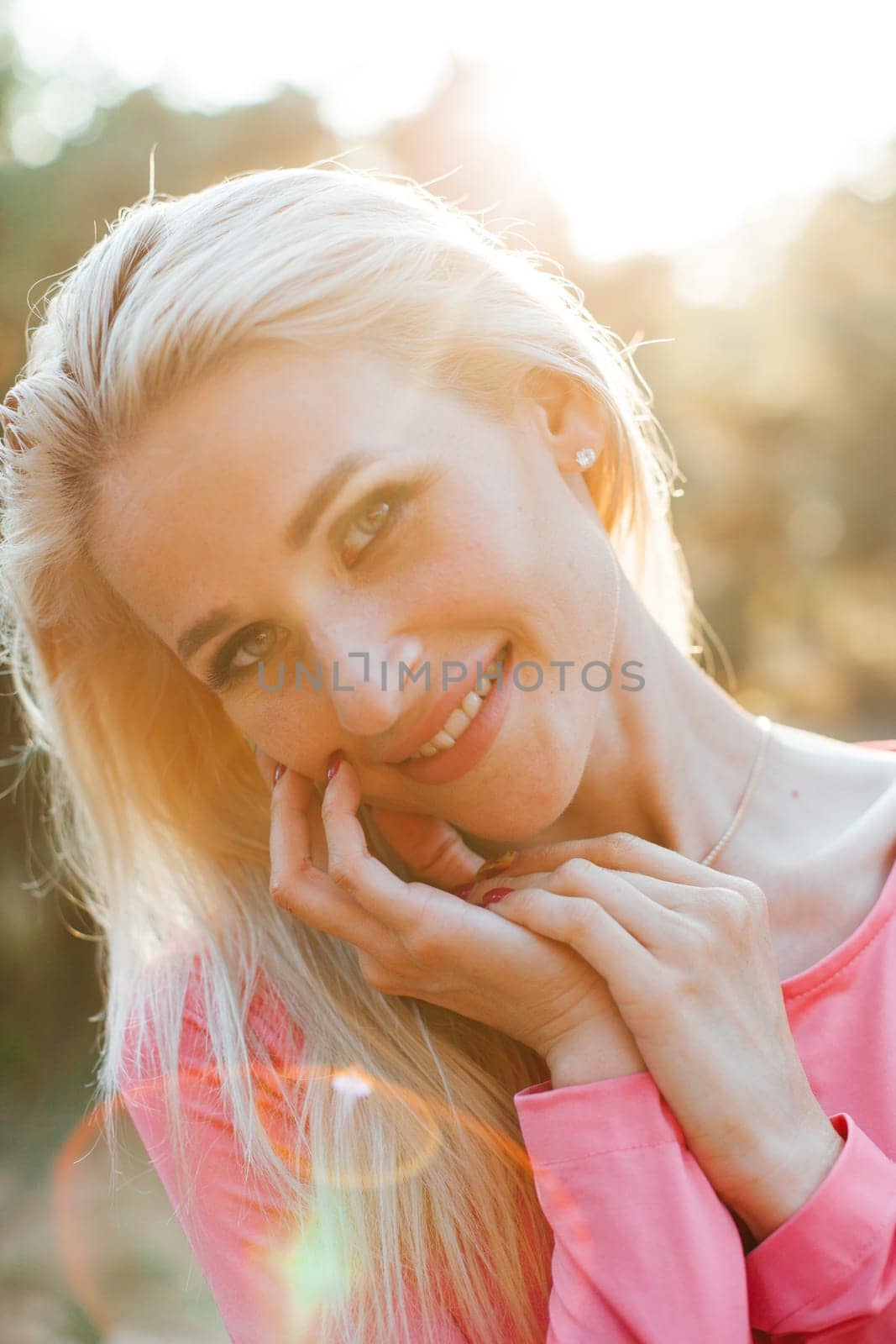 Portrait of blonde woman in pink dress in park on walk
