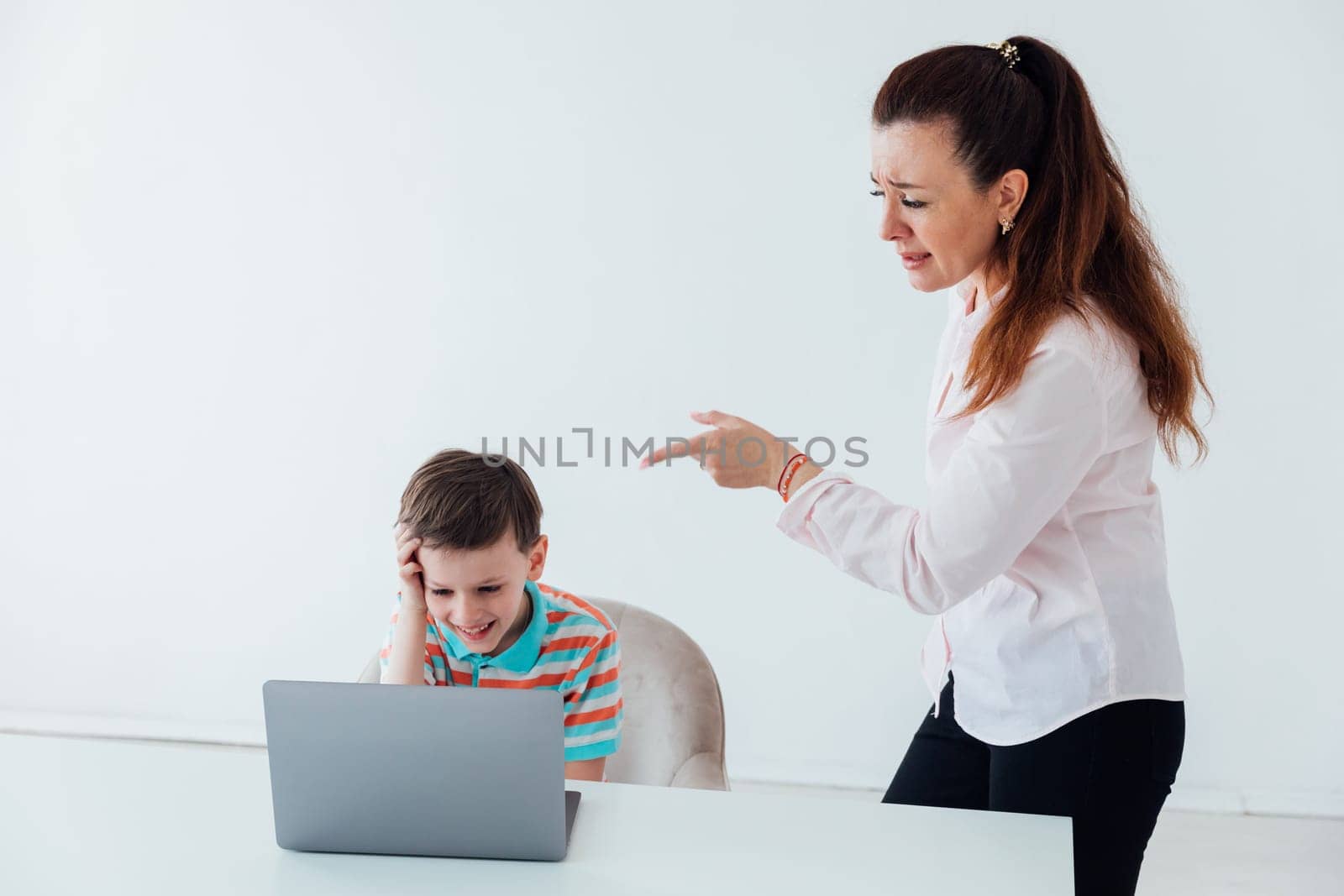 Woman talking to boy at table laptop