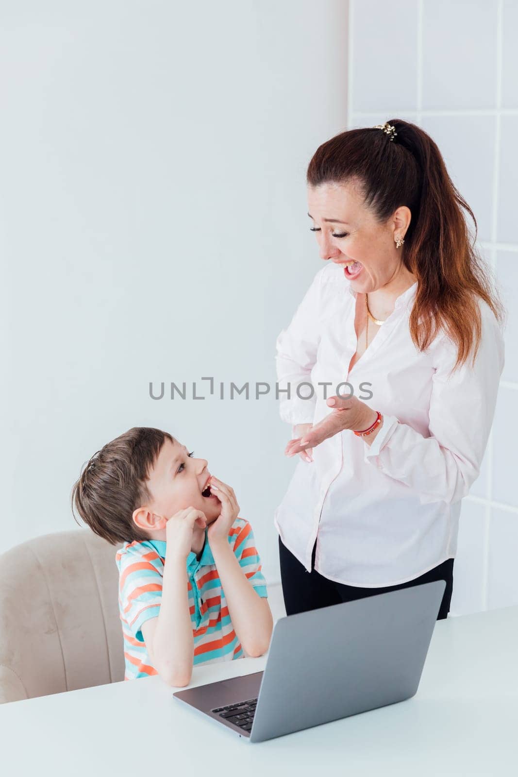 Woman talking to boy at table laptop
