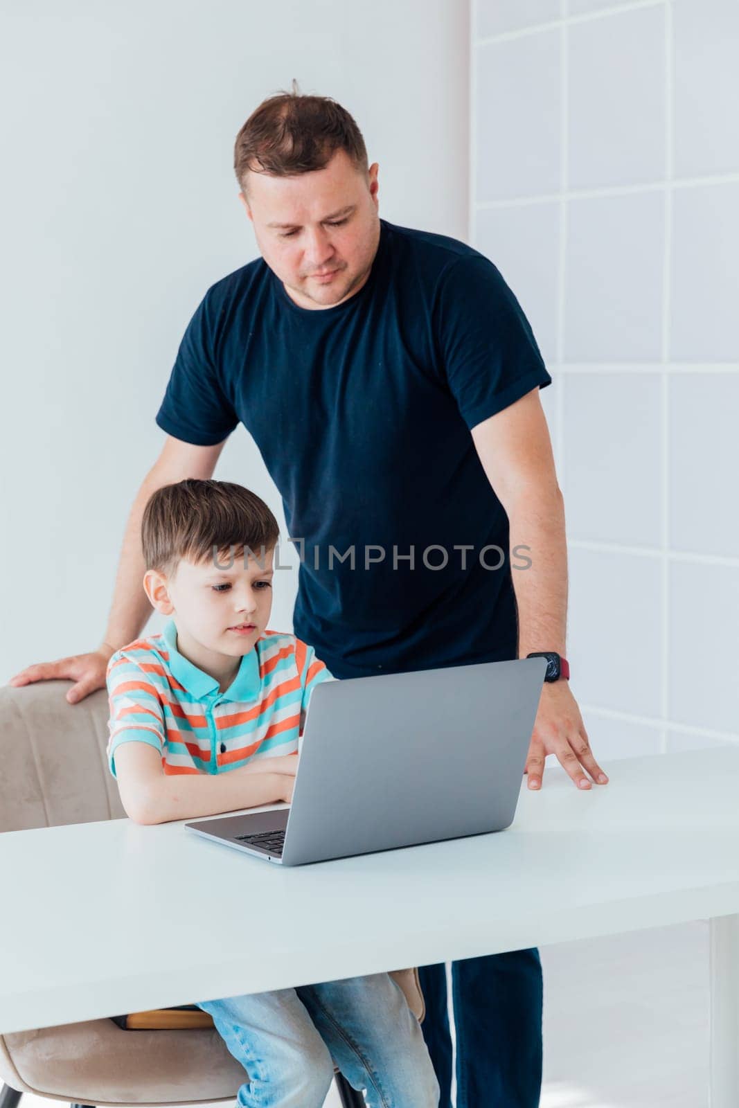 Male teacher teaches child at desk laptop