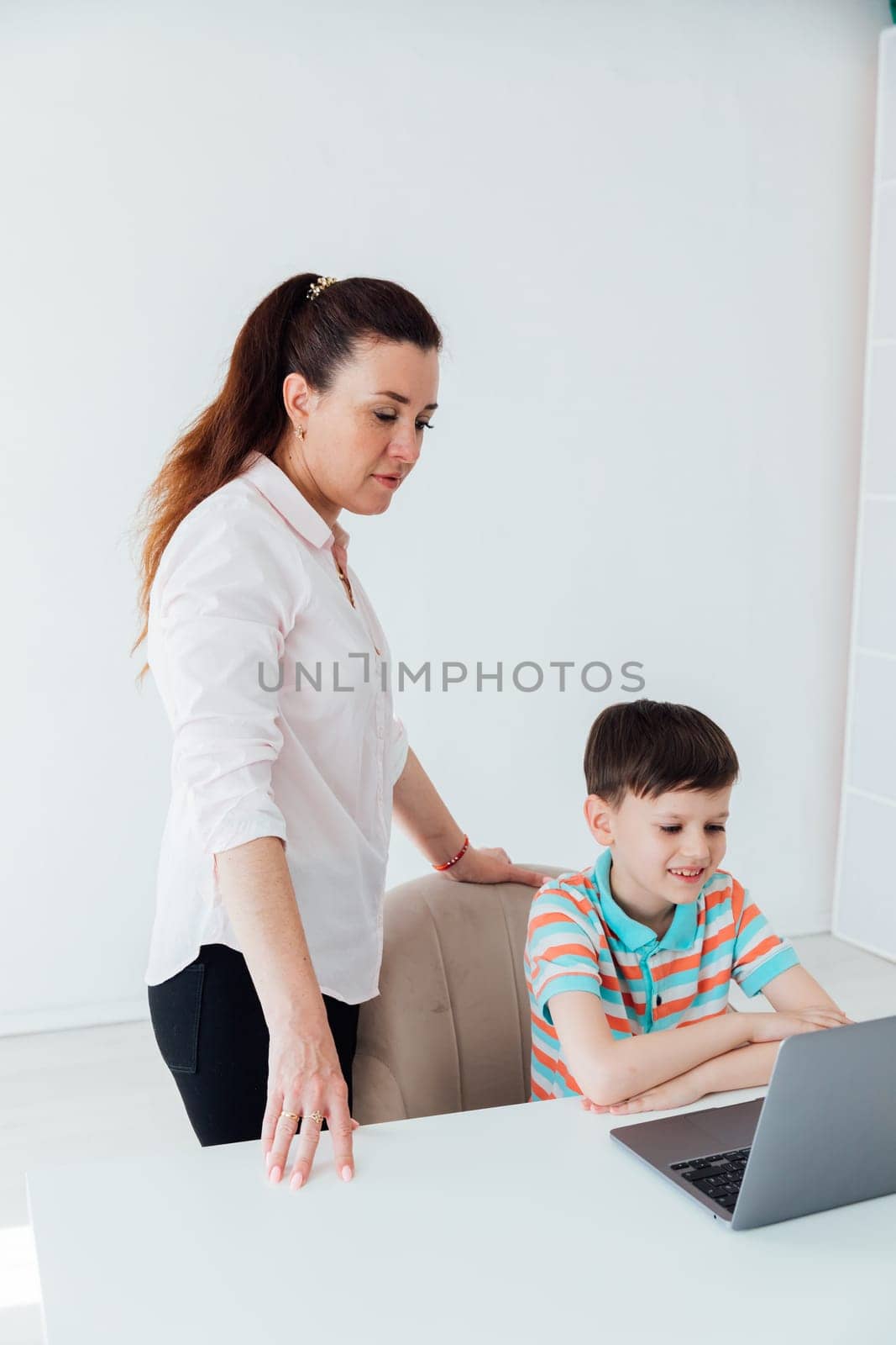 Mom helps her son do school assignment on computer