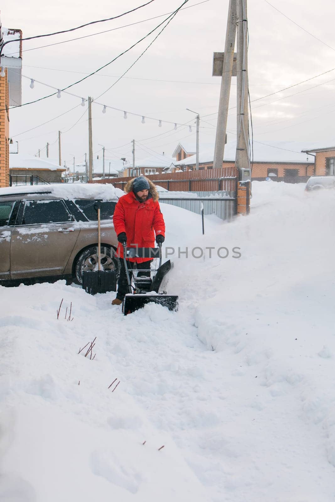 A man clear snow from backyard with snow blower. Winter season and snow blower equipment.