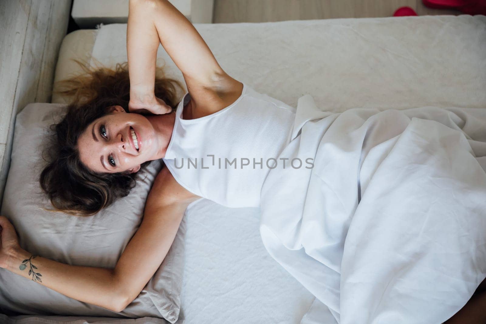 Woman sleeping. High angle view of beautiful young woman lying in bed and keeping eyes closed while covered with blanket. Stock photo
