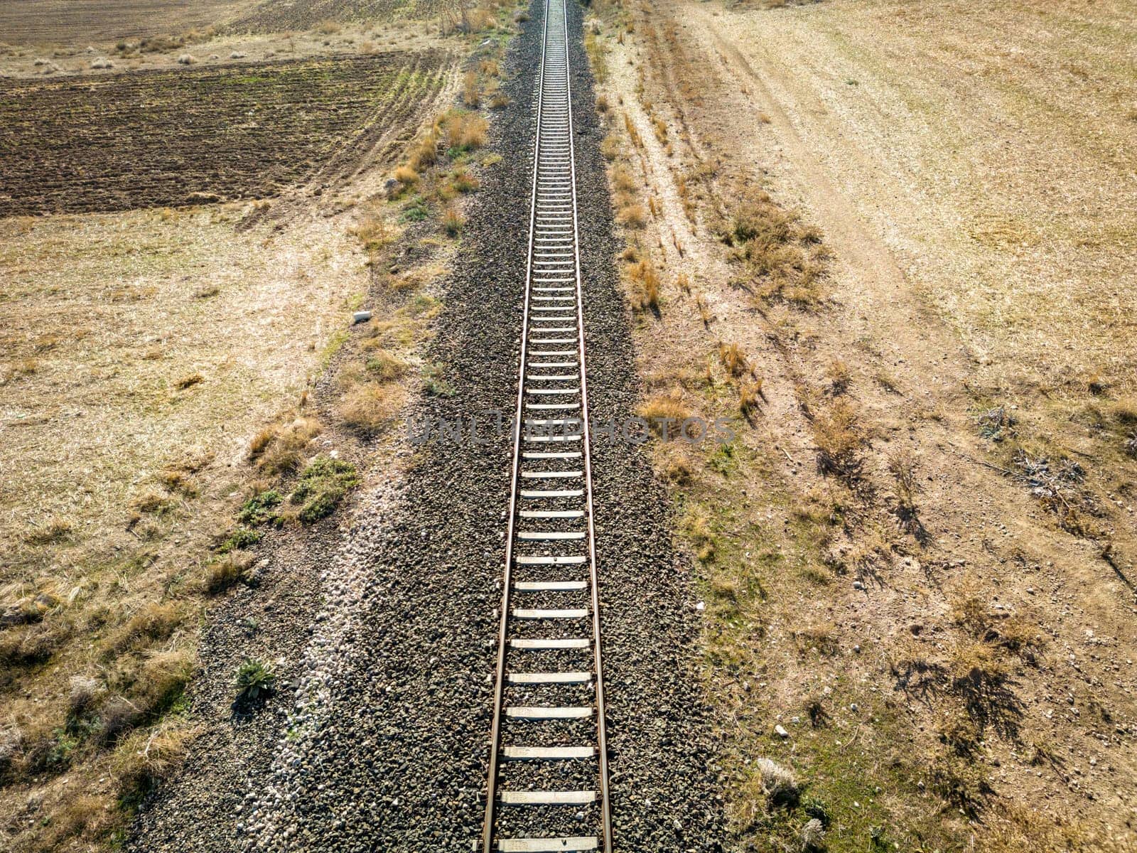 Top view of the train track passing through the arid land, taken with a drone by Sonat