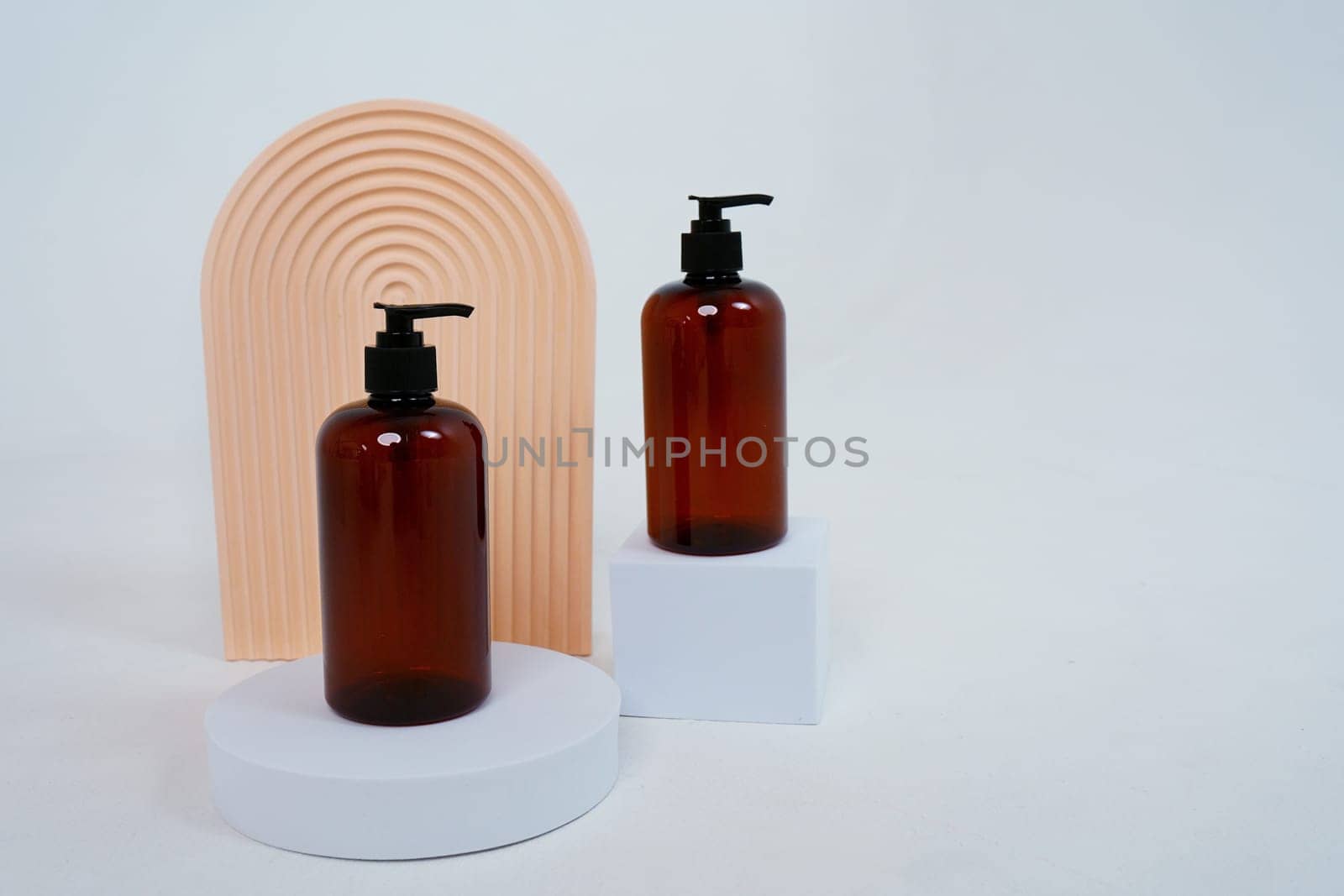 Composition with geometric shapes and natural body care cosmetics. glass bottles with dispenser standing on a light gray background. by tewolf