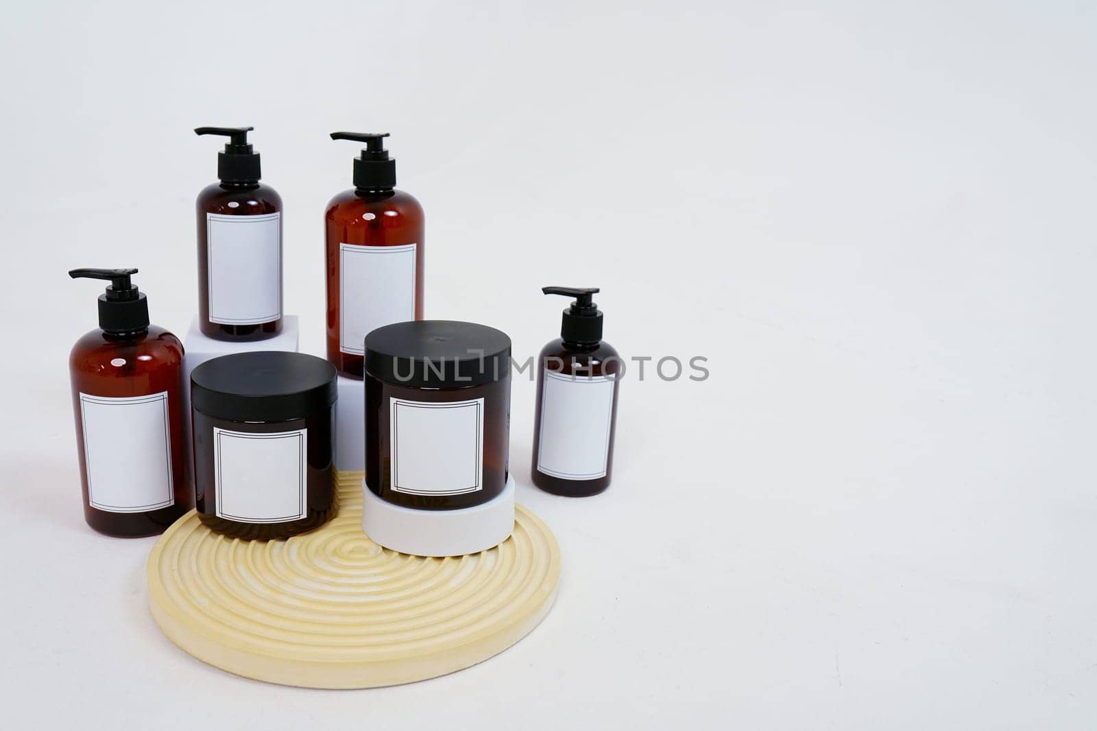 Body care. a set of bottles with dispensers and jars of body cream on a geometric stand and on a light gray background. Advertising concept by tewolf