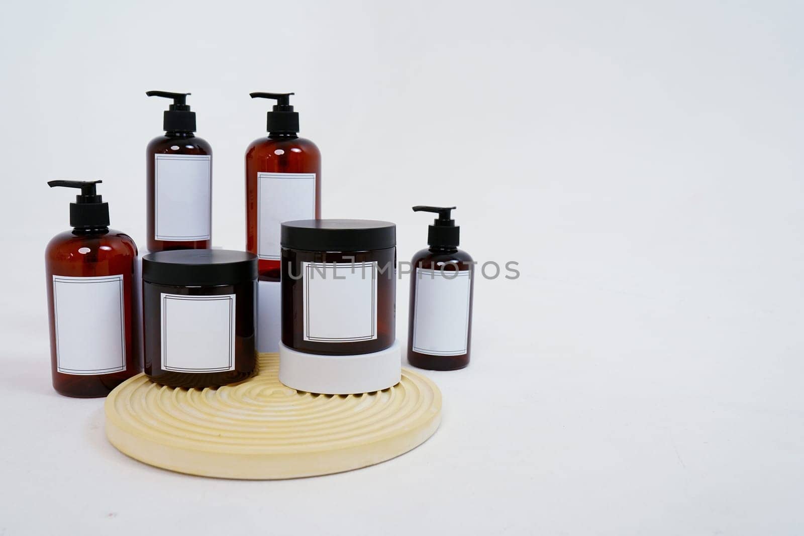 Body care. a set of bottles with dispensers and jars of body cream on a geometric stand and on a light gray background. Advertising concept by tewolf