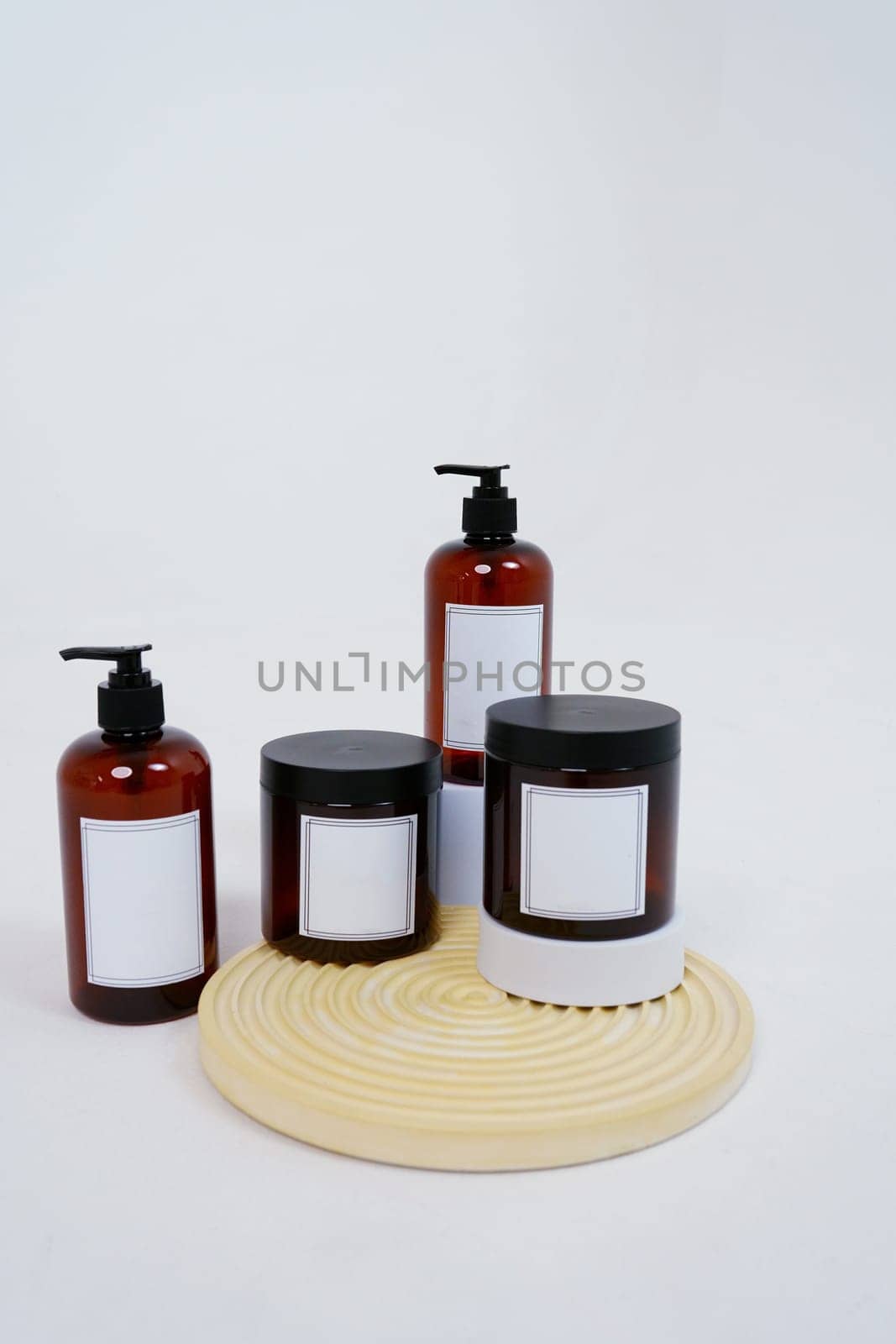 Body care. a set of bottles with dispensers and jars of body cream on a geometric stand and on a light gray background. Advertising concept by tewolf