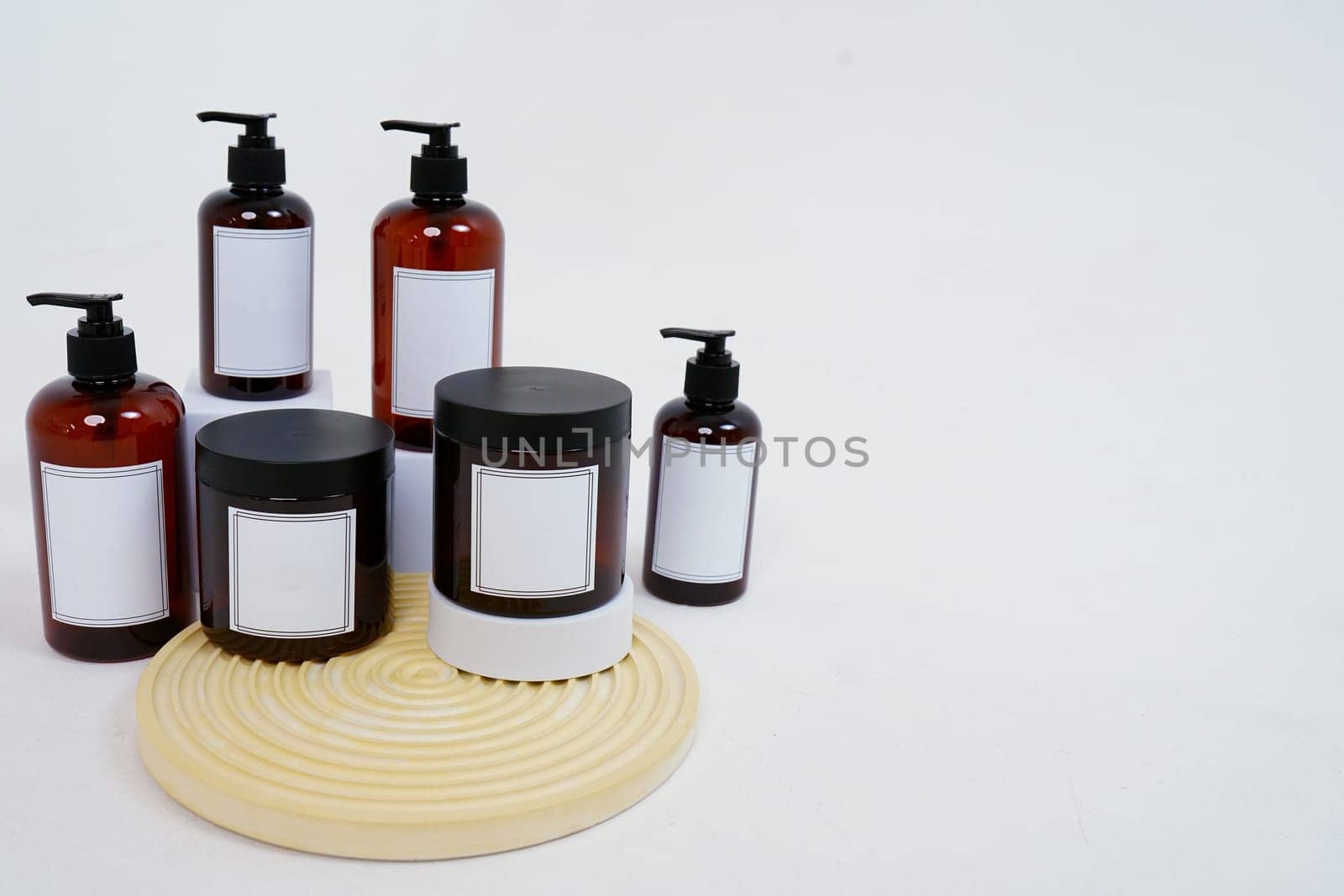 Body care. a set of bottles with dispensers and jars of body cream on a geometric stand and on a light gray background. Advertising concept. High quality photo