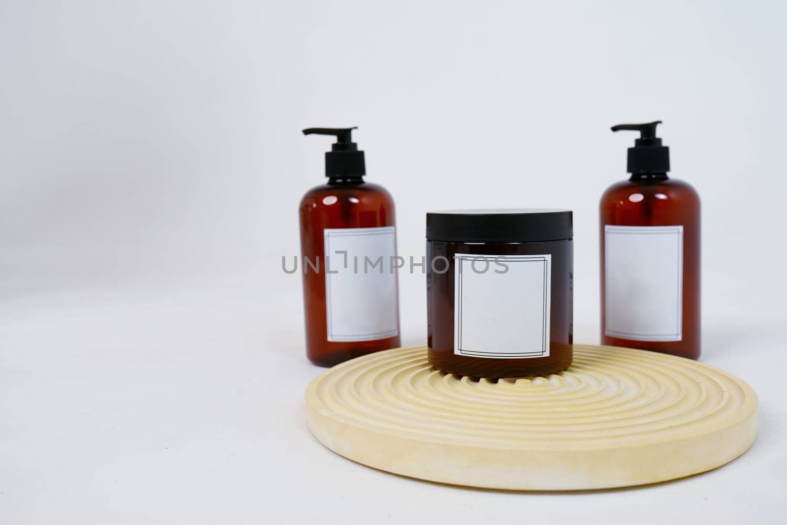 Body care. two bottles with a dispenser and a jar of body cream on a geometric stand on a light gray background. Advertising concept. High quality photo