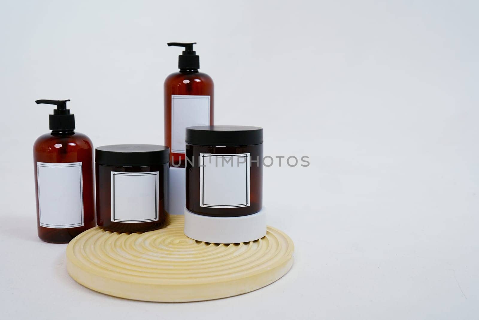 Body care. a set of bottles with dispensers and jars of body cream on a geometric stand and on a light gray background. Advertising concept by tewolf