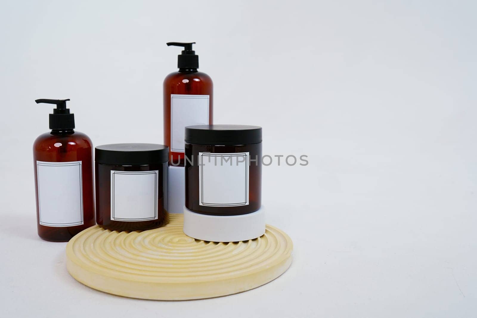 Body care. a set of bottles with dispensers and jars of body cream on a geometric stand and on a light gray background. Advertising concept. High quality photo