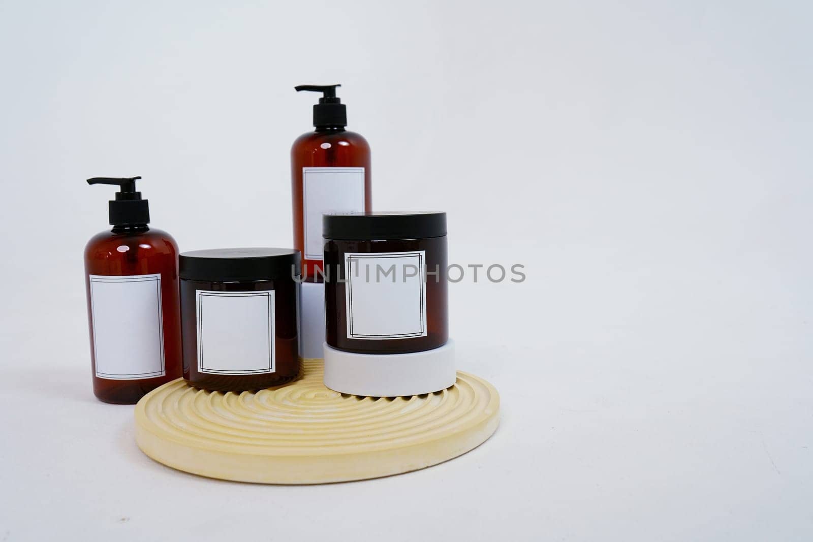 Body care. a set of bottles with dispensers and jars of body cream on a geometric stand and on a light gray background. Advertising concept by tewolf