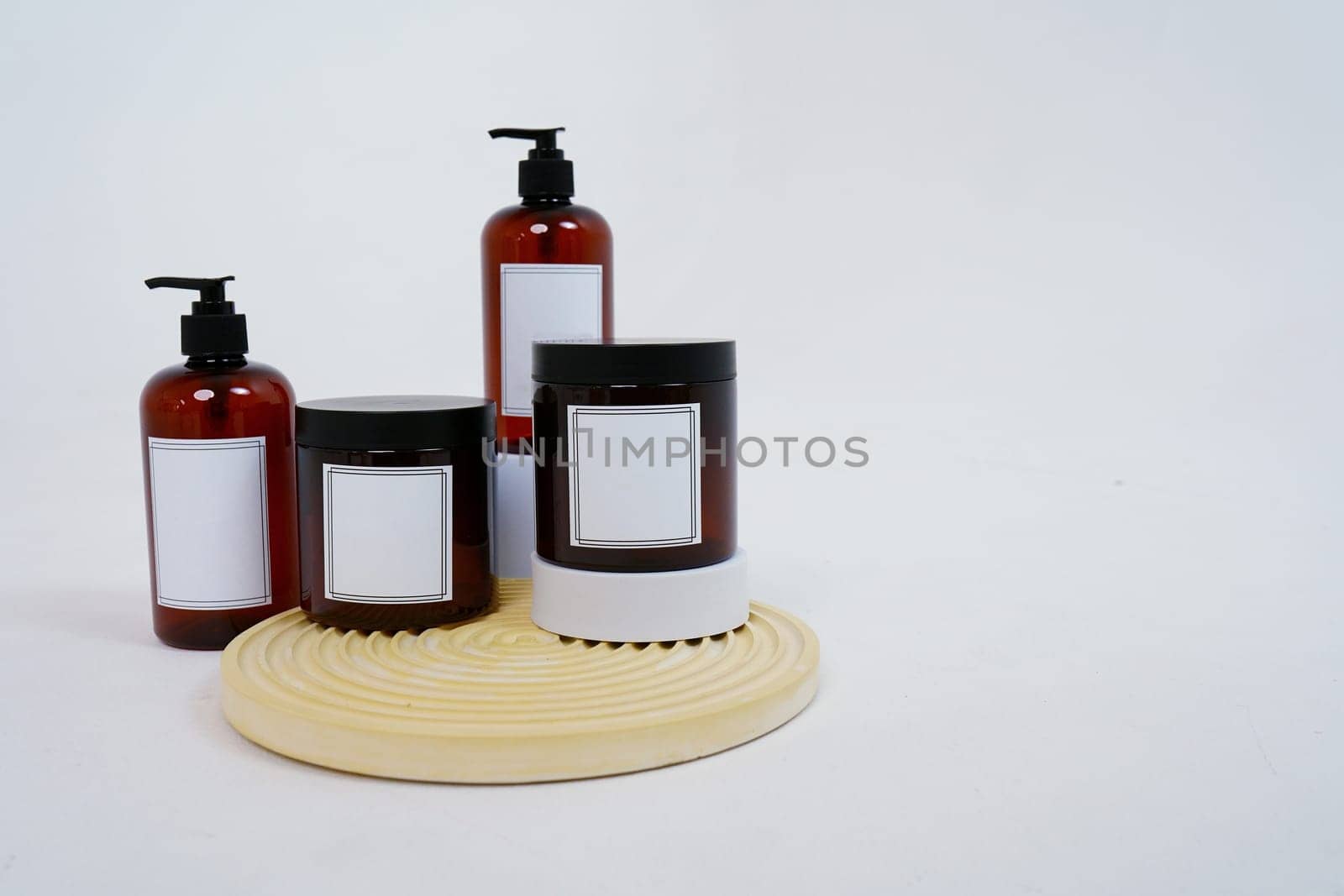 Body care. a set of bottles with dispensers and jars of body cream on a geometric stand and on a light gray background. Advertising concept by tewolf