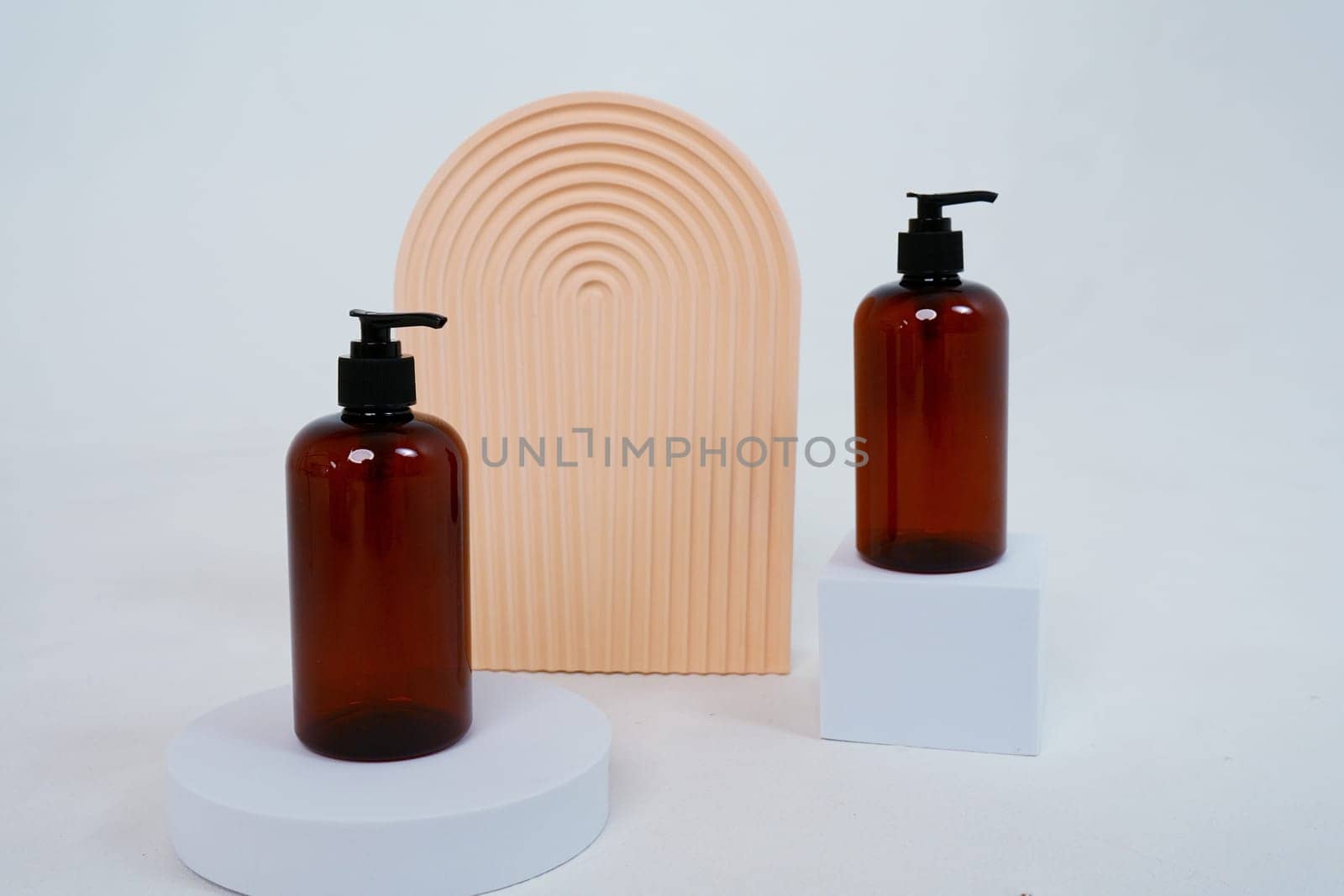 Composition with geometric shapes and natural body care cosmetics. glass bottles with dispenser standing on a light gray background. by tewolf