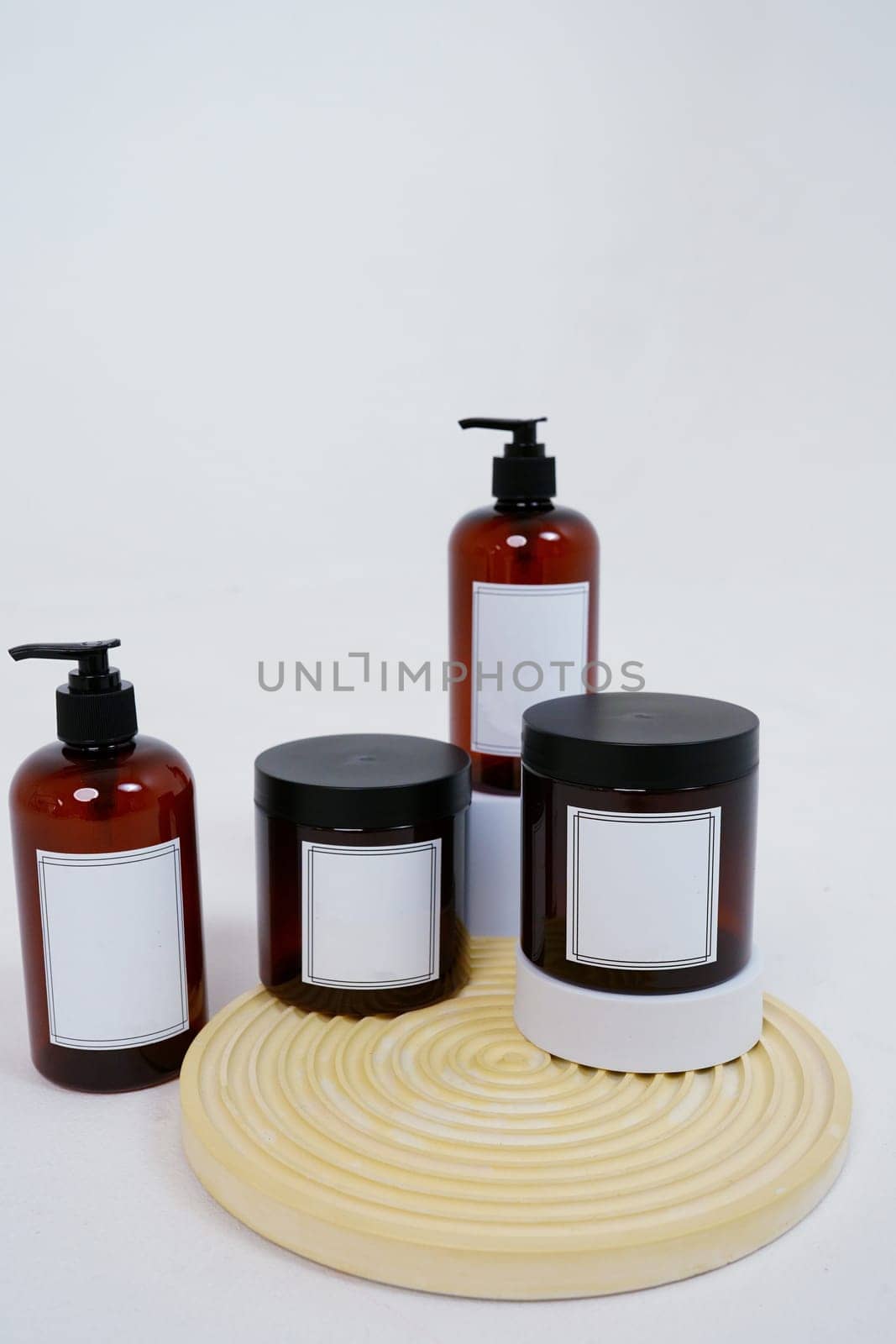 Body care. a set of bottles with dispensers and jars of body cream on a geometric stand and on a light gray background. Advertising concept. High quality photo