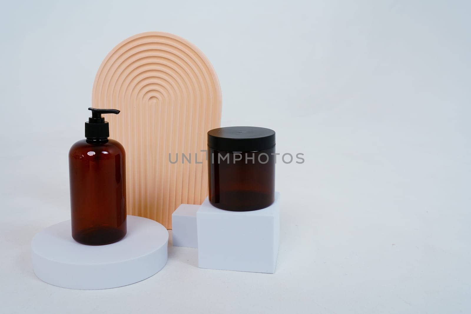 Composition with geometric shapes.body care. bottle with a dispenser and a jar of cream, on a light gray background. Advertising concept by tewolf