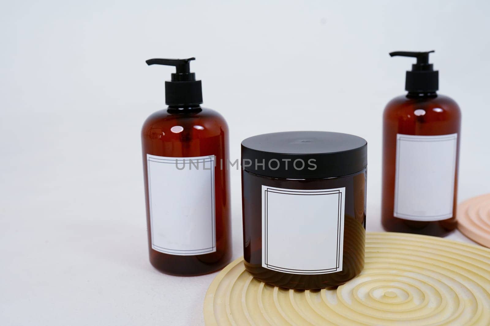 Body care. two bottles with a dispenser and a jar of body cream on a geometric stand on a light gray background. Advertising concept. High quality photo