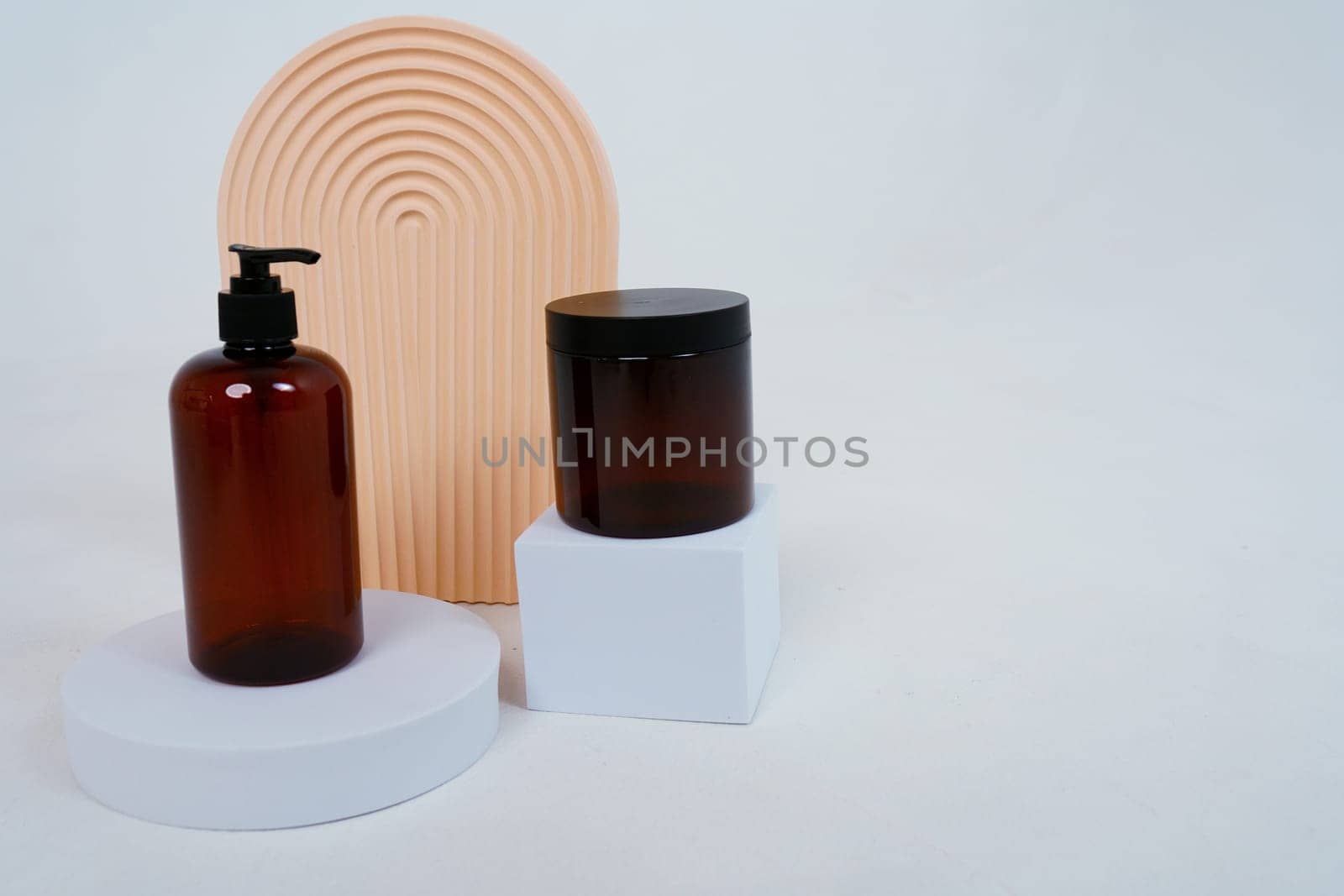 Composition with geometric shapes.body care. bottle with a dispenser and a jar of cream, on a light gray background. Advertising concept by tewolf