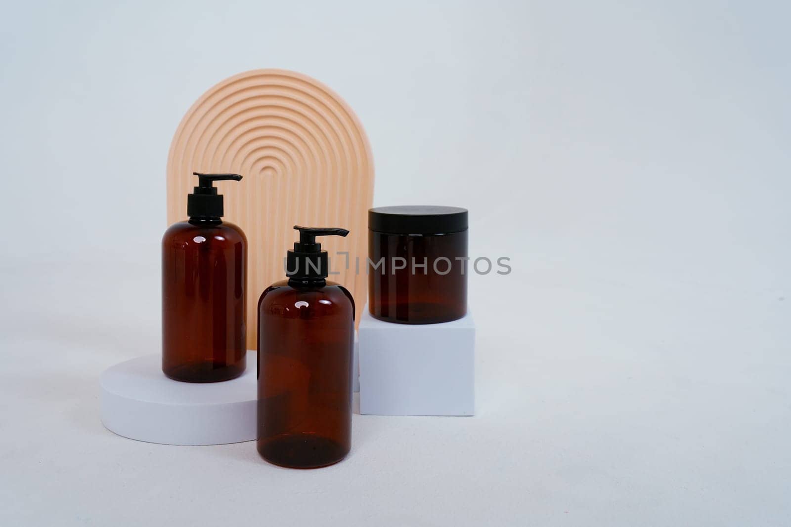 Composition with geometric shapes.body care. two bottles with a dispenser and a jar of cream, on a light gray background. Advertising concept by tewolf