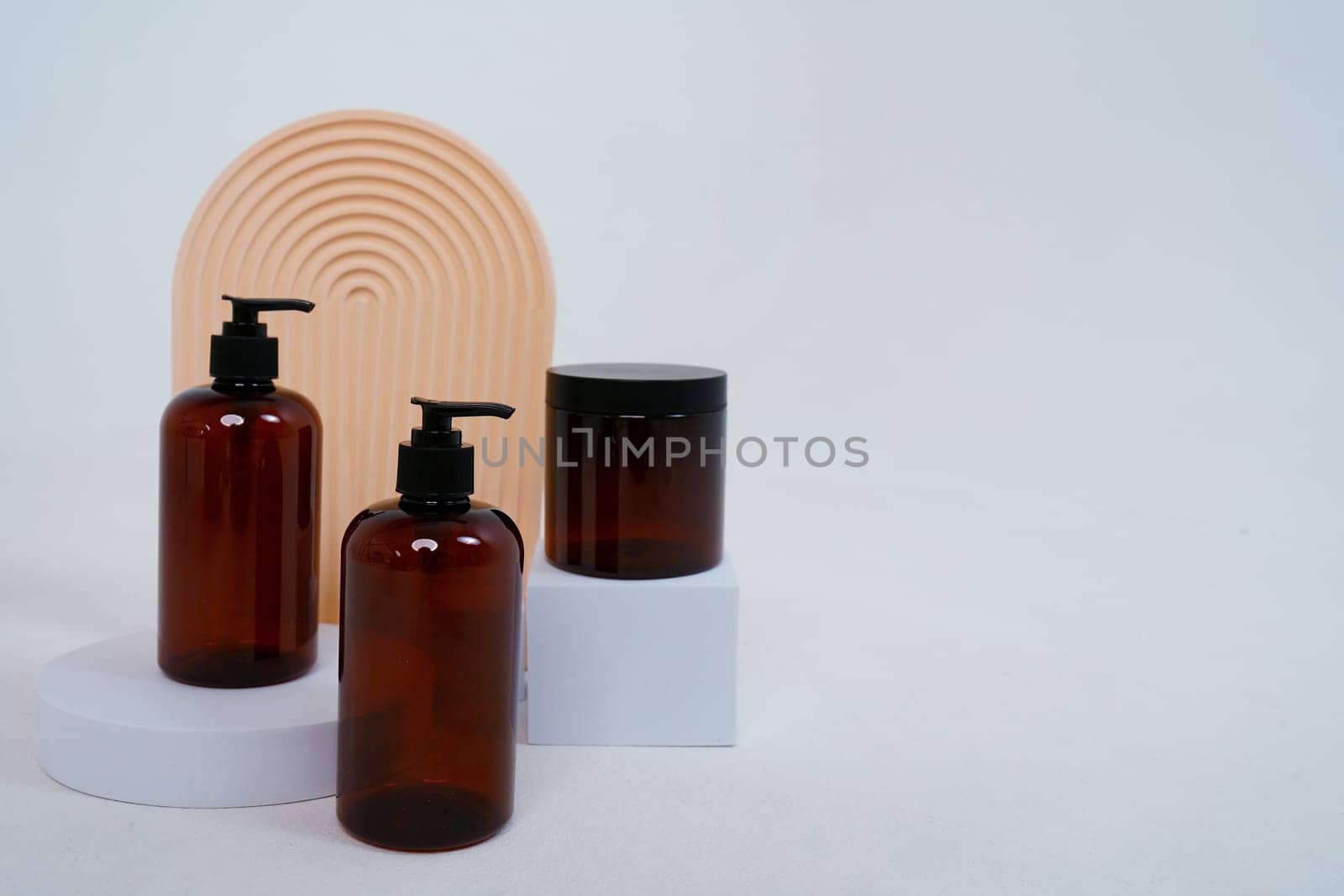 Composition with geometric shapes.body care. two bottles with a dispenser and a jar of cream, on a light gray background. Advertising concept. High quality photo