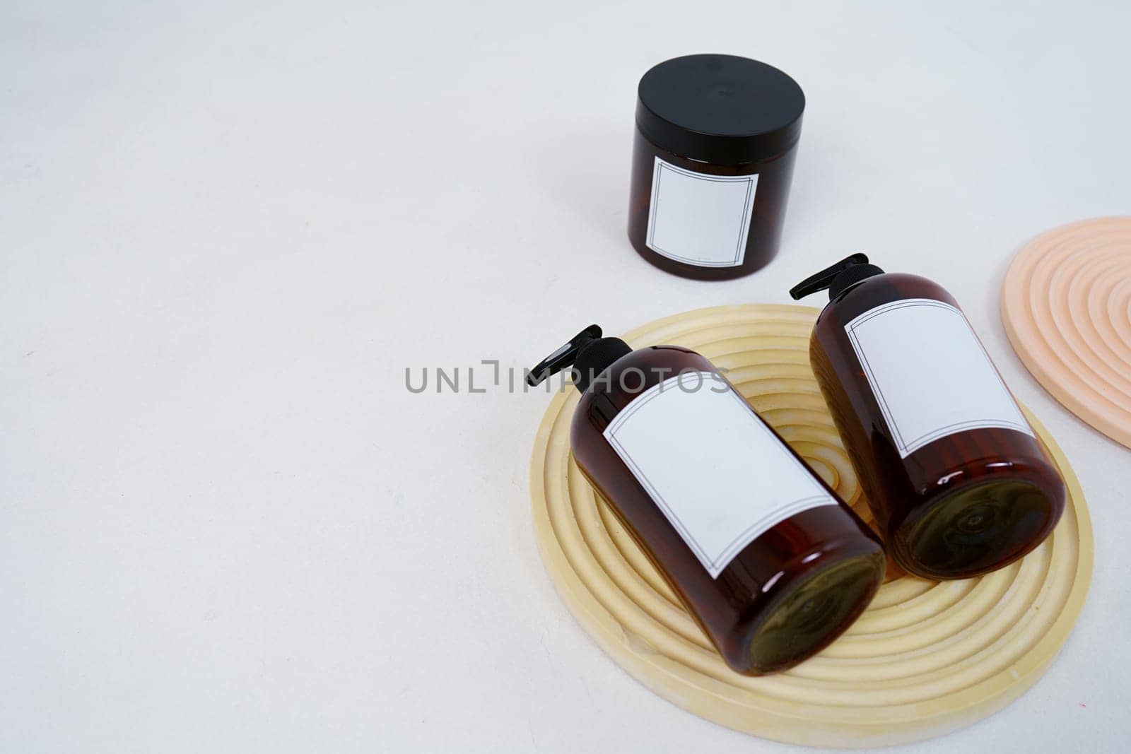 Body care. two bottles with a dispenser and a jar of body cream on a geometric stand on a light gray background. Advertising concept. High quality photo