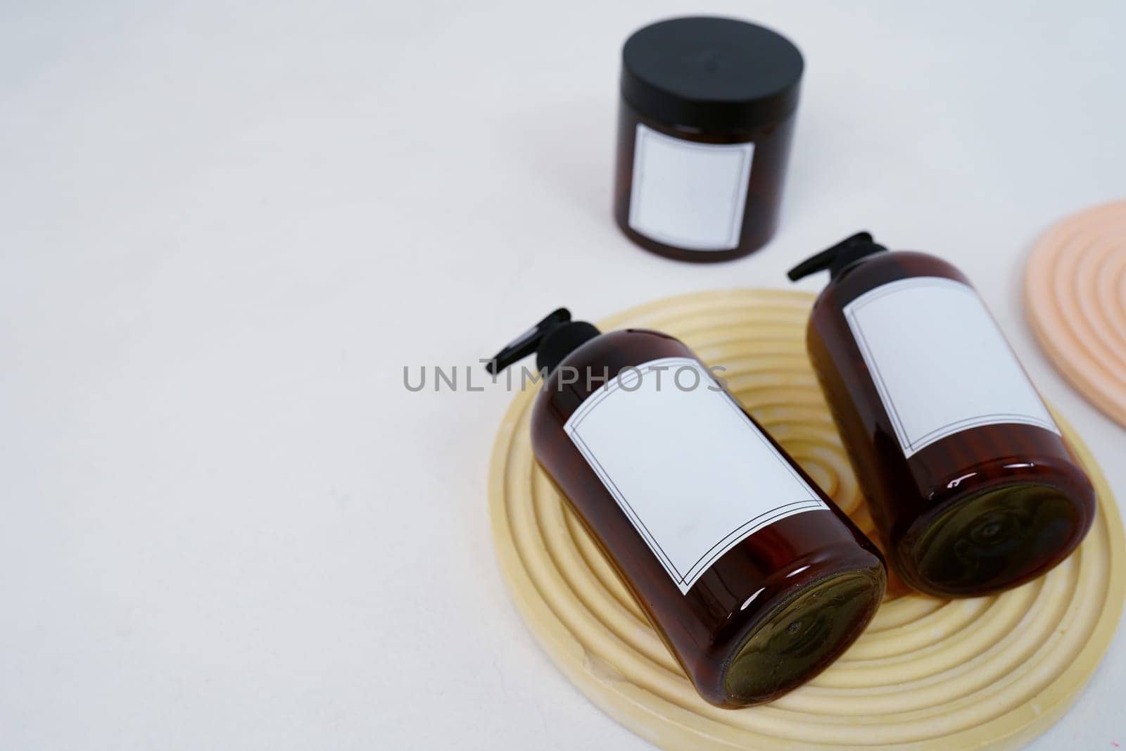 Body care. two bottles with a dispenser and a jar of body cream on a geometric stand on a light gray background. Advertising concept by tewolf