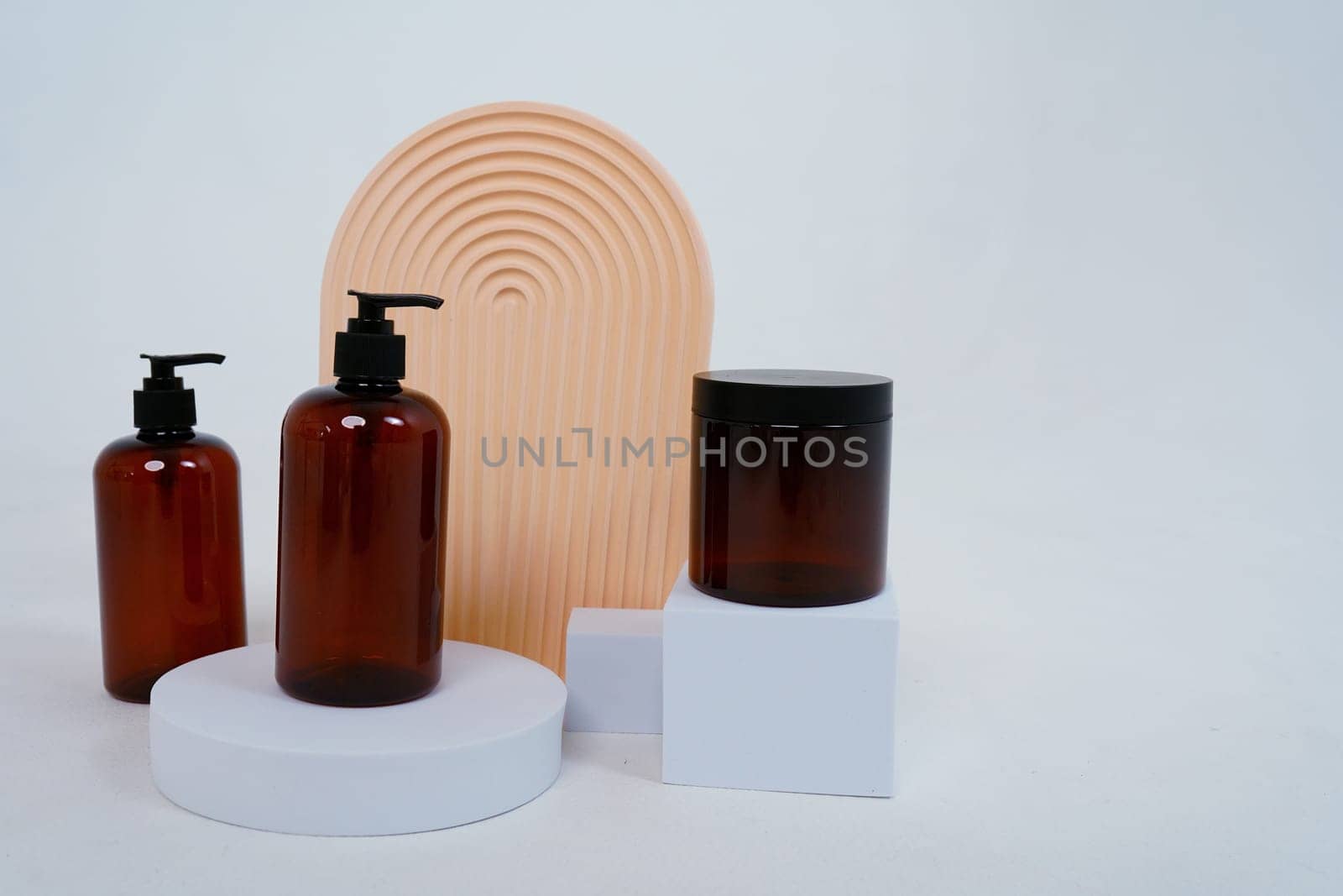 Composition with geometric shapes.body care. two bottles with a dispenser and a jar of cream, on a light gray background. Advertising concept. High quality photo