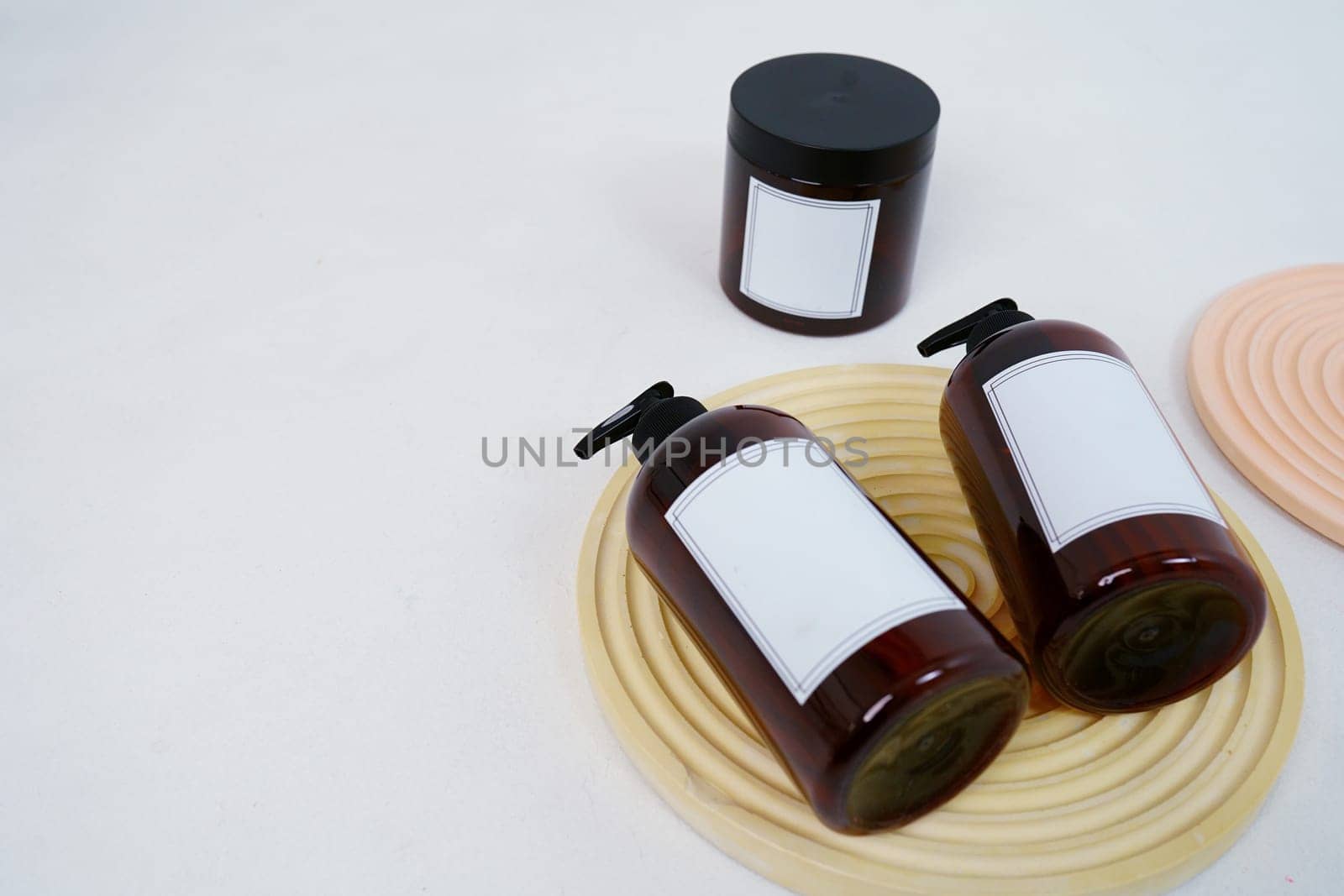 Body care. two bottles with a dispenser and a jar of body cream on a geometric stand on a light gray background. Advertising concept. High quality photo