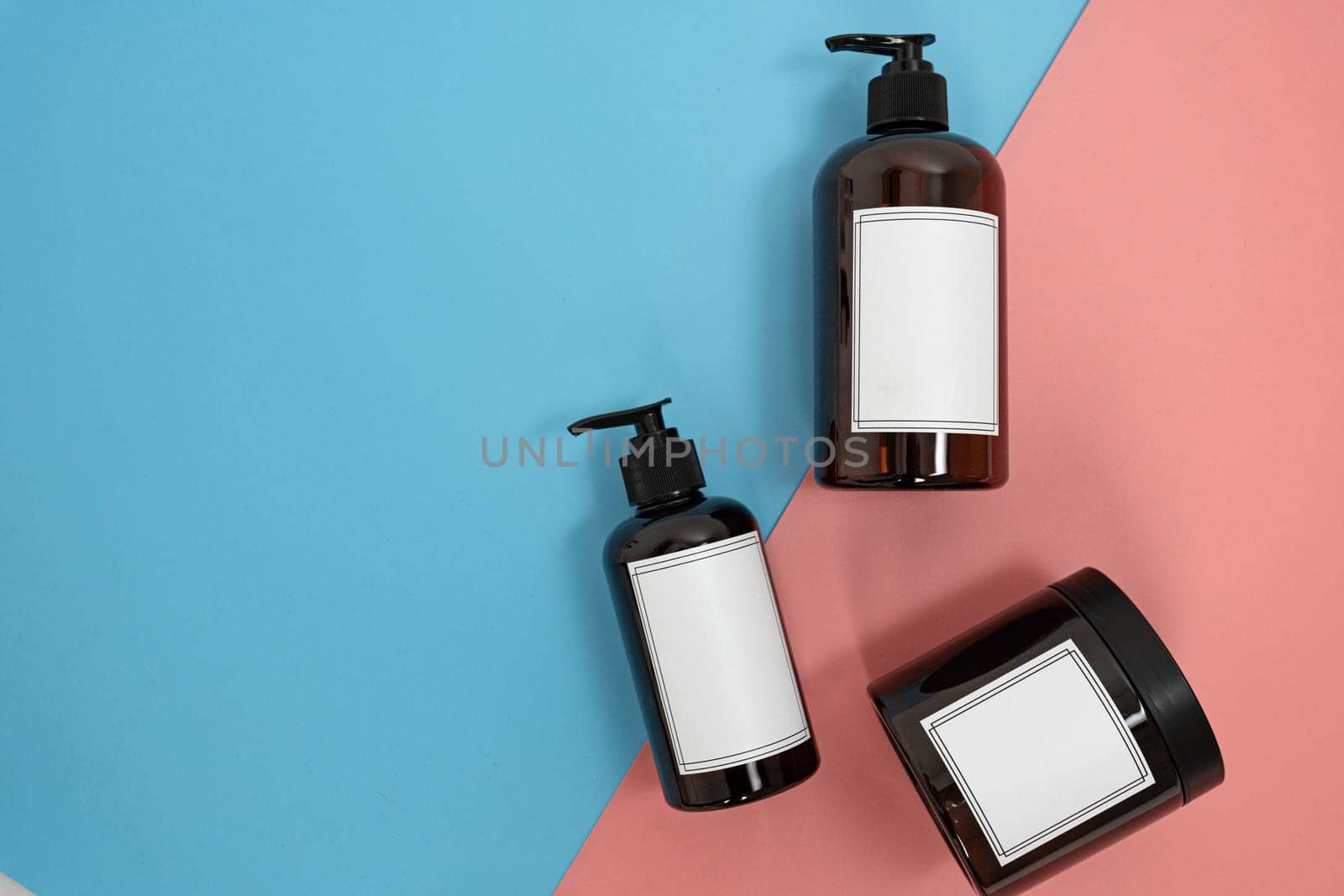 Body care. set of bottles with dispensers and jars of body cream on a blue and pink background. Advertising concept by tewolf