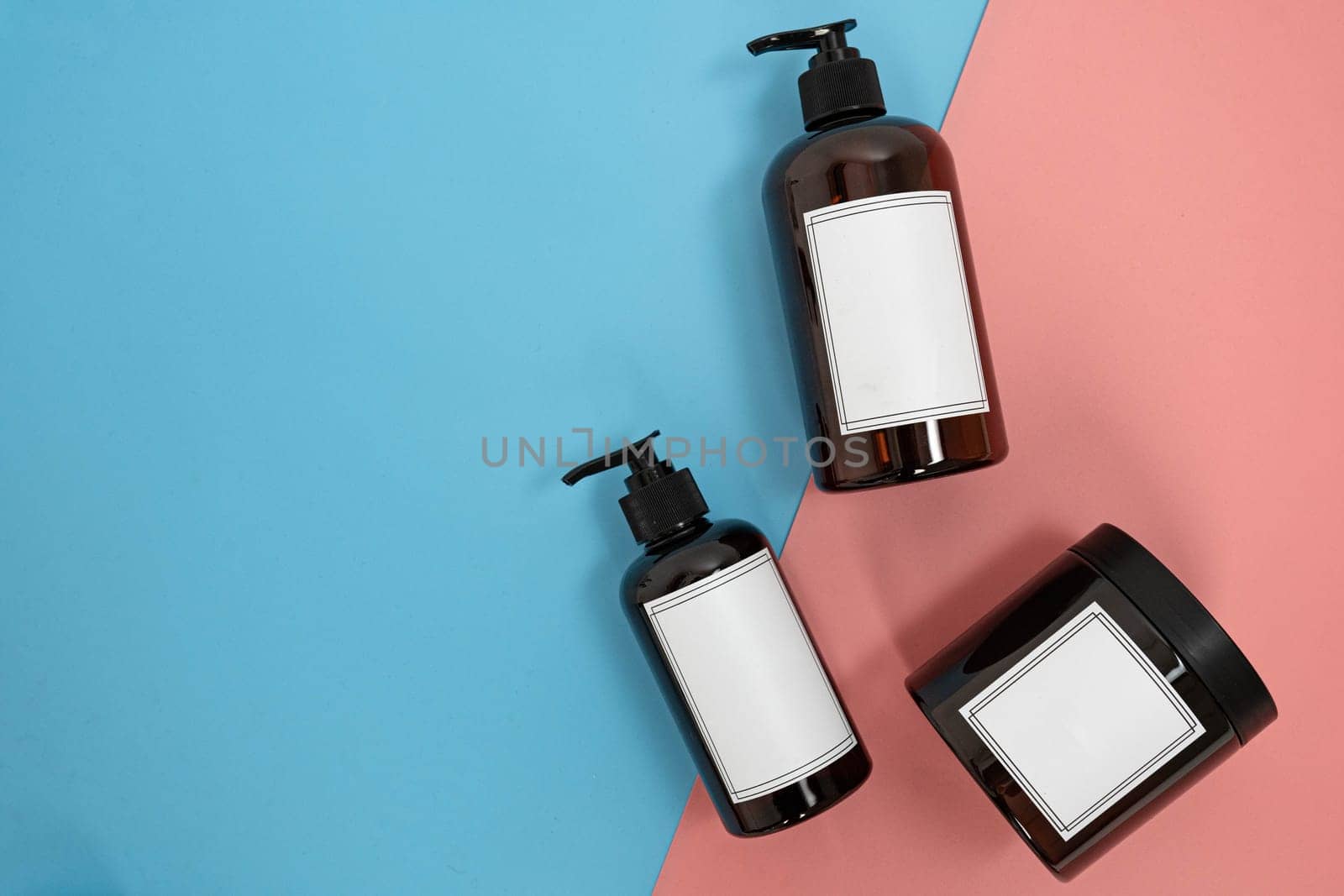 Body care. set of bottles with dispensers and jars of body cream on a blue and pink background. Advertising concept by tewolf