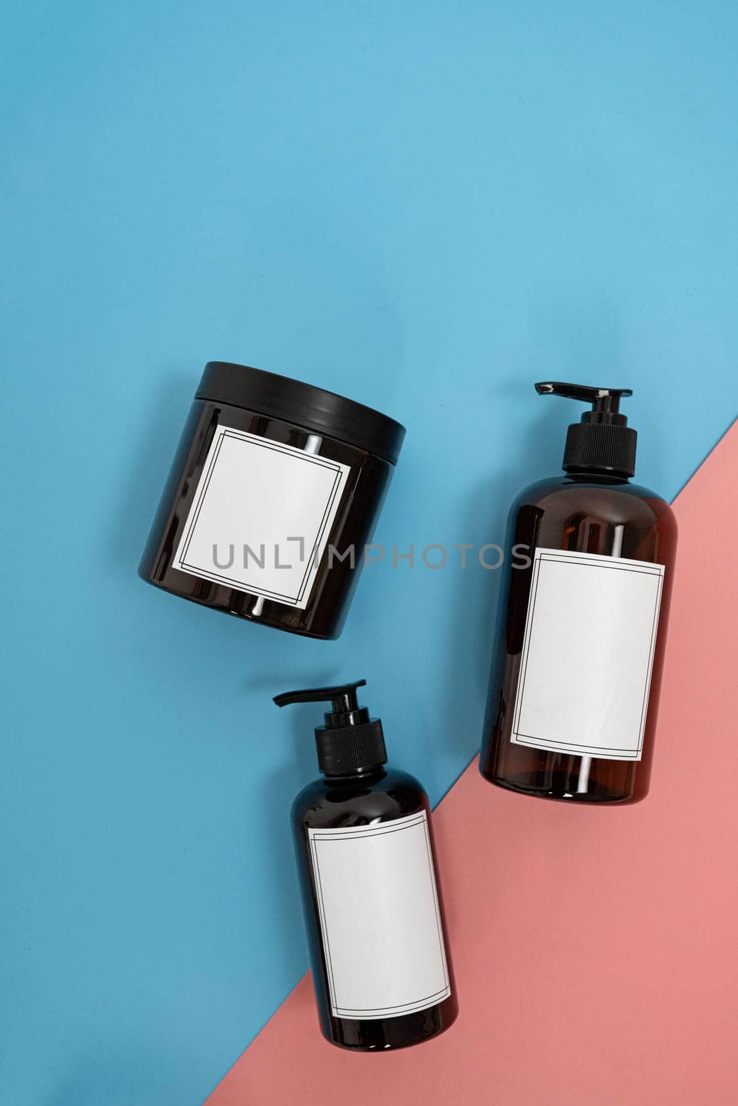 Body care. set of bottles with dispensers and jars of body cream on a blue and pink background. Advertising concept by tewolf