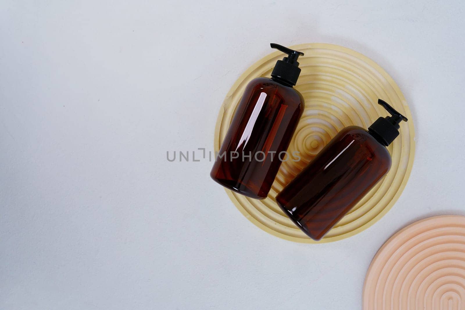 Two dark bottles for shampoo or cosmetics on a light background and round coasters. View from the top. High quality photo