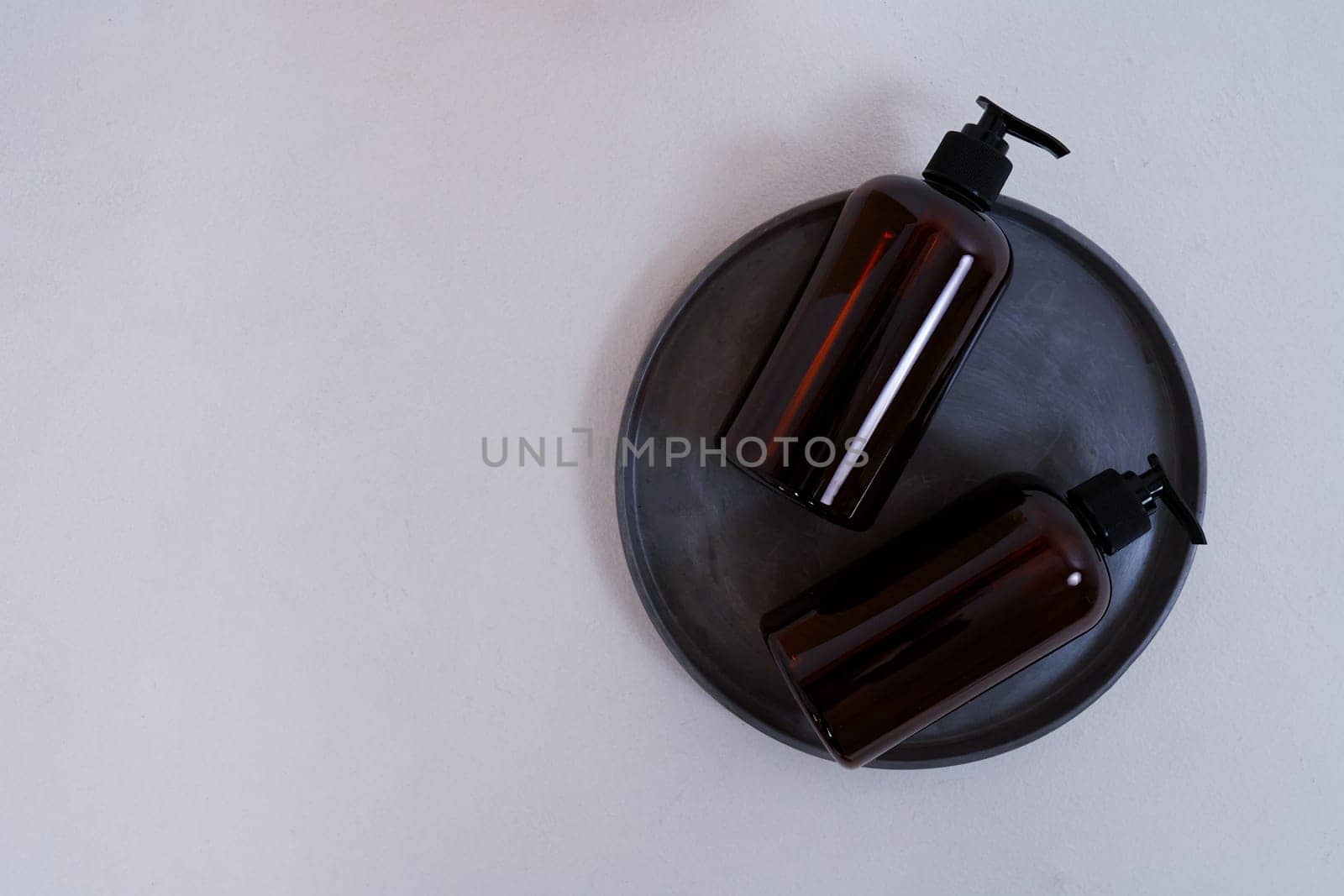 Composition with geometric shapes. Body care. two bottles with a dispenser on a black plate on a light gray background. Advertising concept. High quality photo