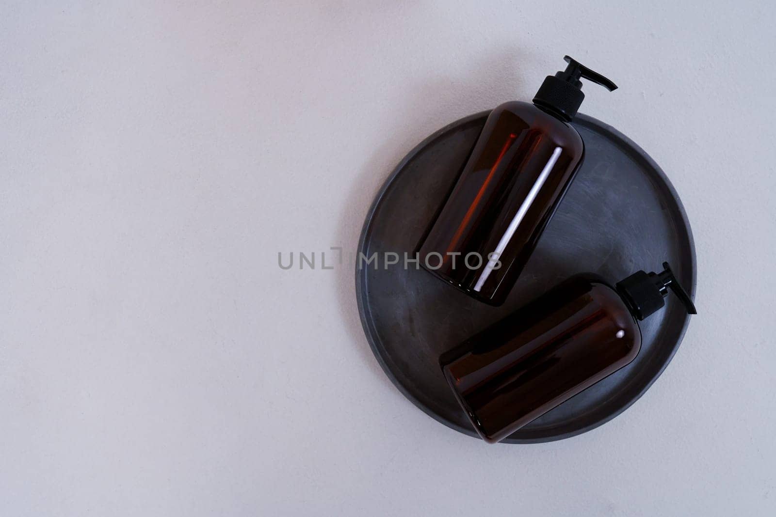 Composition with geometric shapes. Body care. two bottles with a dispenser on a black plate on a light gray background. Advertising concept by tewolf